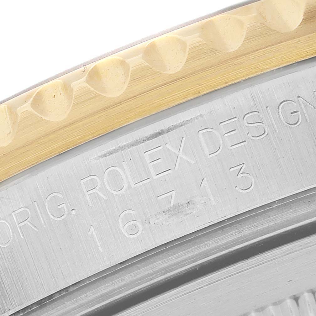 The image shows a close-up of the case and bezel edge of a Rolex GMT-Master 16713LN Men's Steel and Gold (two tone) Black Dial, highlighting the engraved model number.