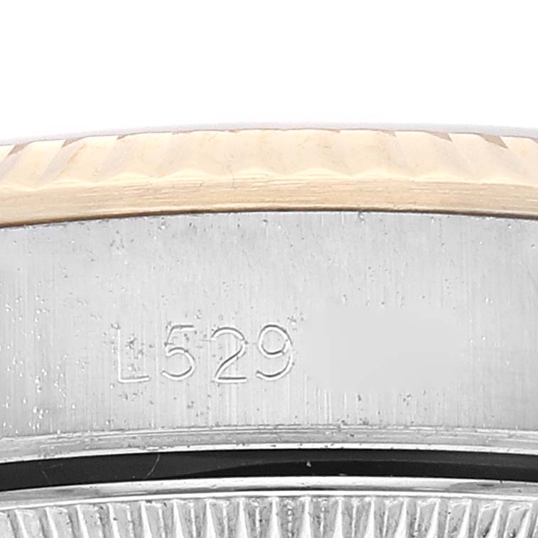 The image shows a close-up view of the side of a Rolex Oyster Perpetual 67193 Women's Steel and Gold (two tone) Champagne Dial 67193 Women's Steel and Gold (two tone) Champagne Dial model watch focusing on its serial number engraved on the case.