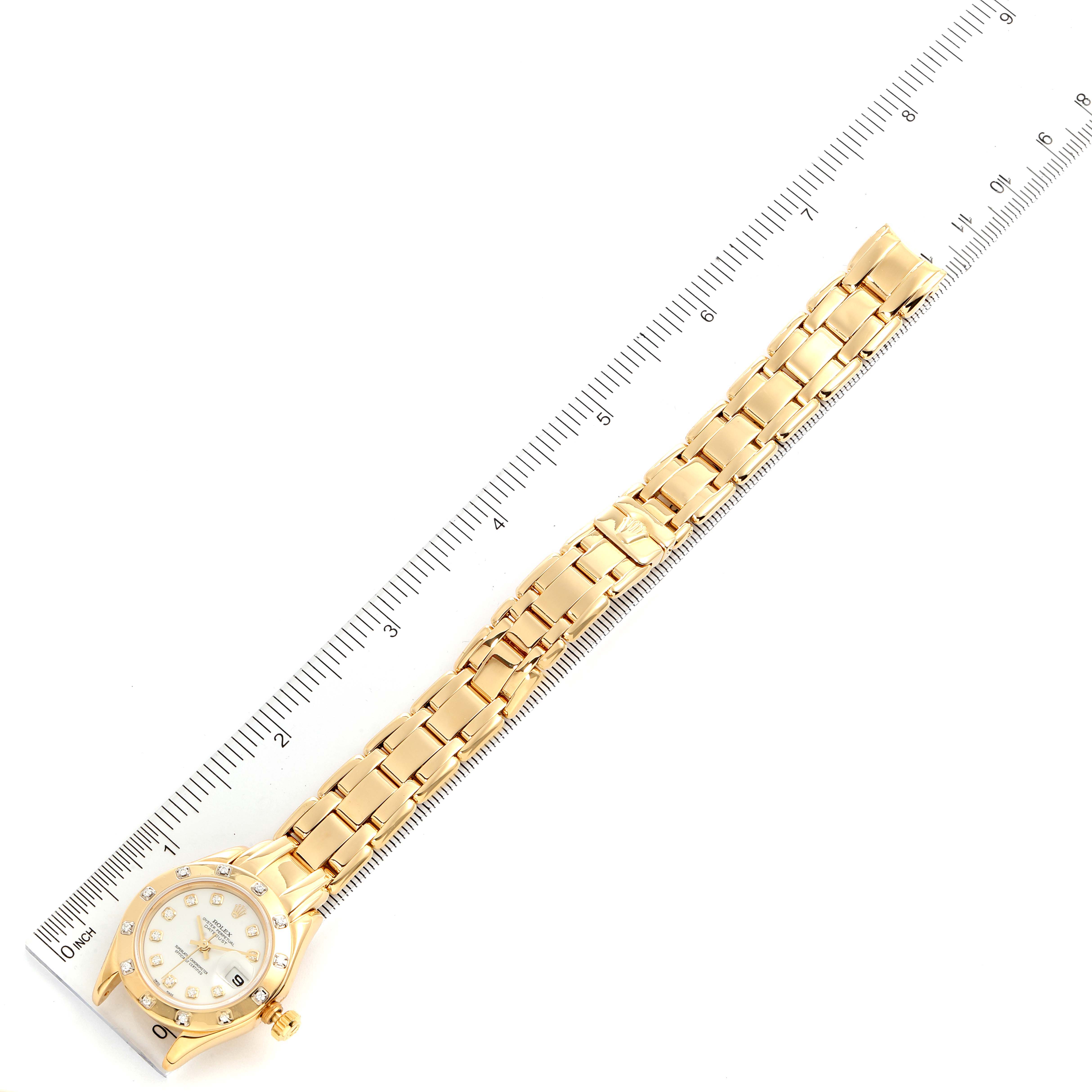 The Rolex Pearlmaster 69318 Women
s Yellow Gold White Dial 69318 Women
s Yellow Gold White Dial watch is shown from a top-down angle, laid out flat next to a ruler for scale.