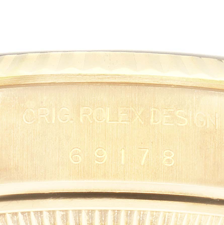 The image shows a close-up of the Rolex President 69178 Women's Yellow Gold Champagne Dial 69178 Women's Yellow Gold Champagne Dial model's side casing with engraved text.