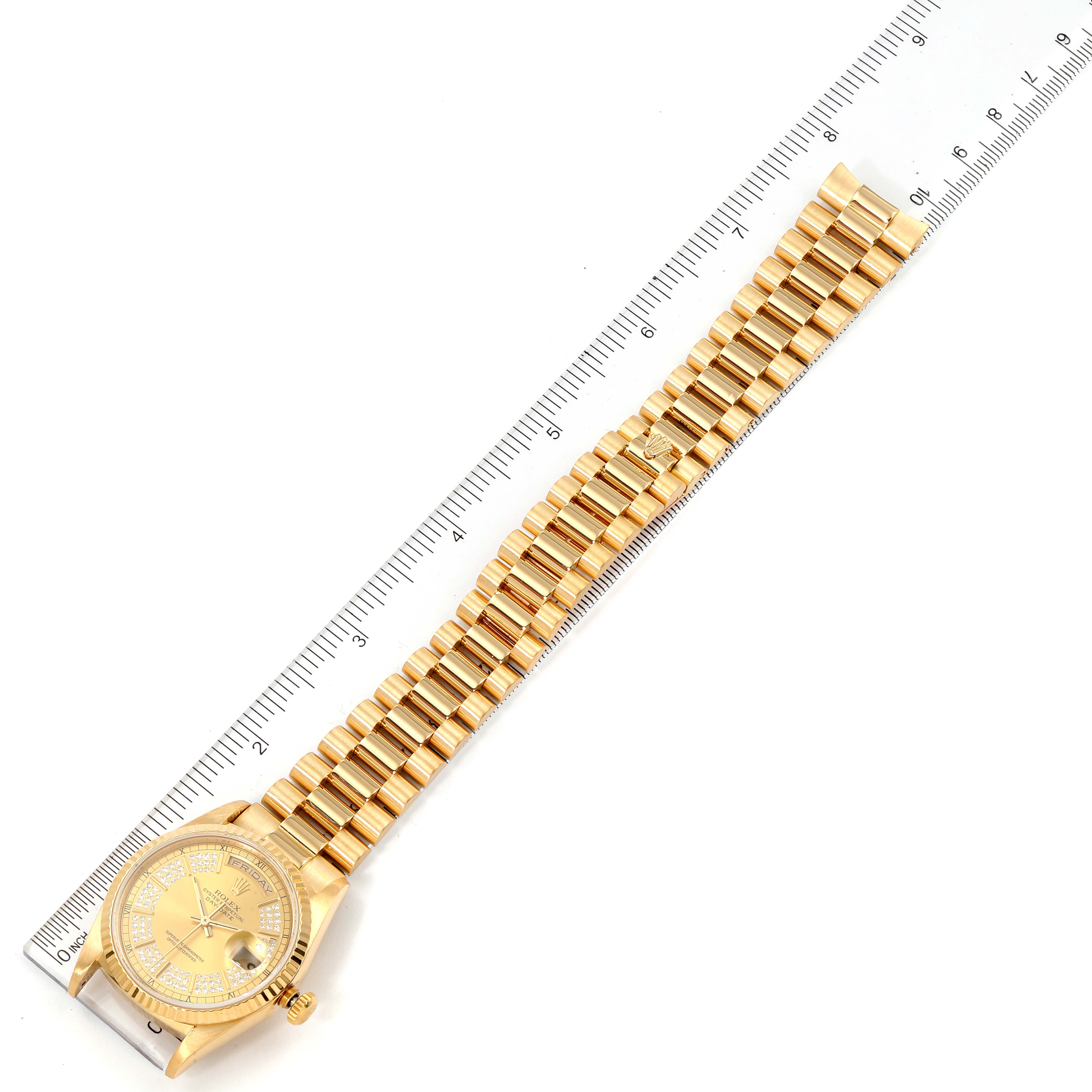 The Rolex President 18238 Men's Yellow Gold Champagne Dial 18238 Men's Yellow Gold Champagne Dial model watch is shown from a top-down angle with its band fully extended next to a ruler.