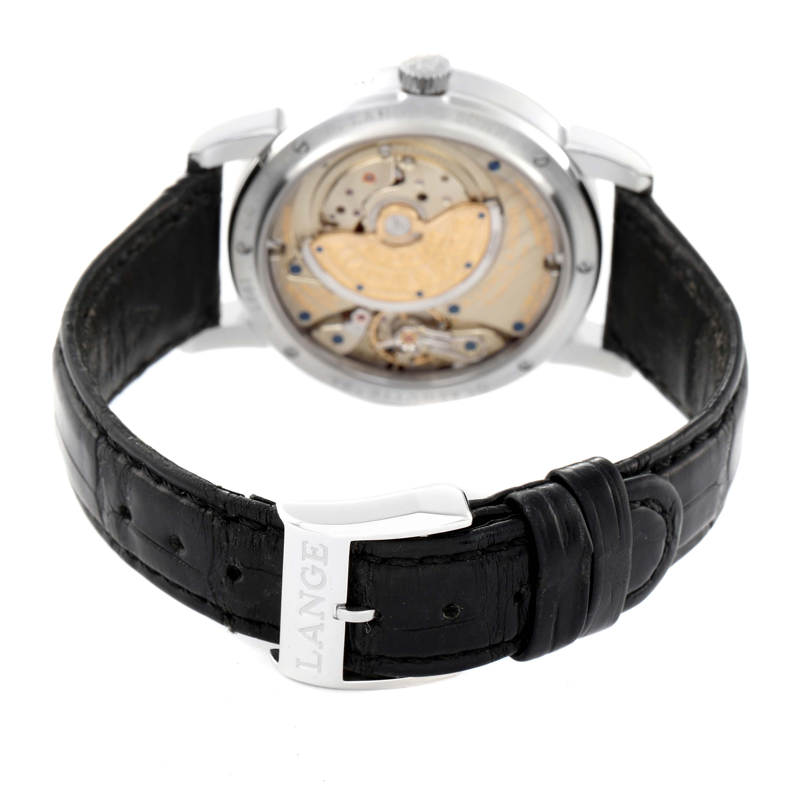 The image shows the back view of the Saxonia watch by A. Lange & Sohne, highlighting the movement and leather strap with "LANGE" on the buckle.