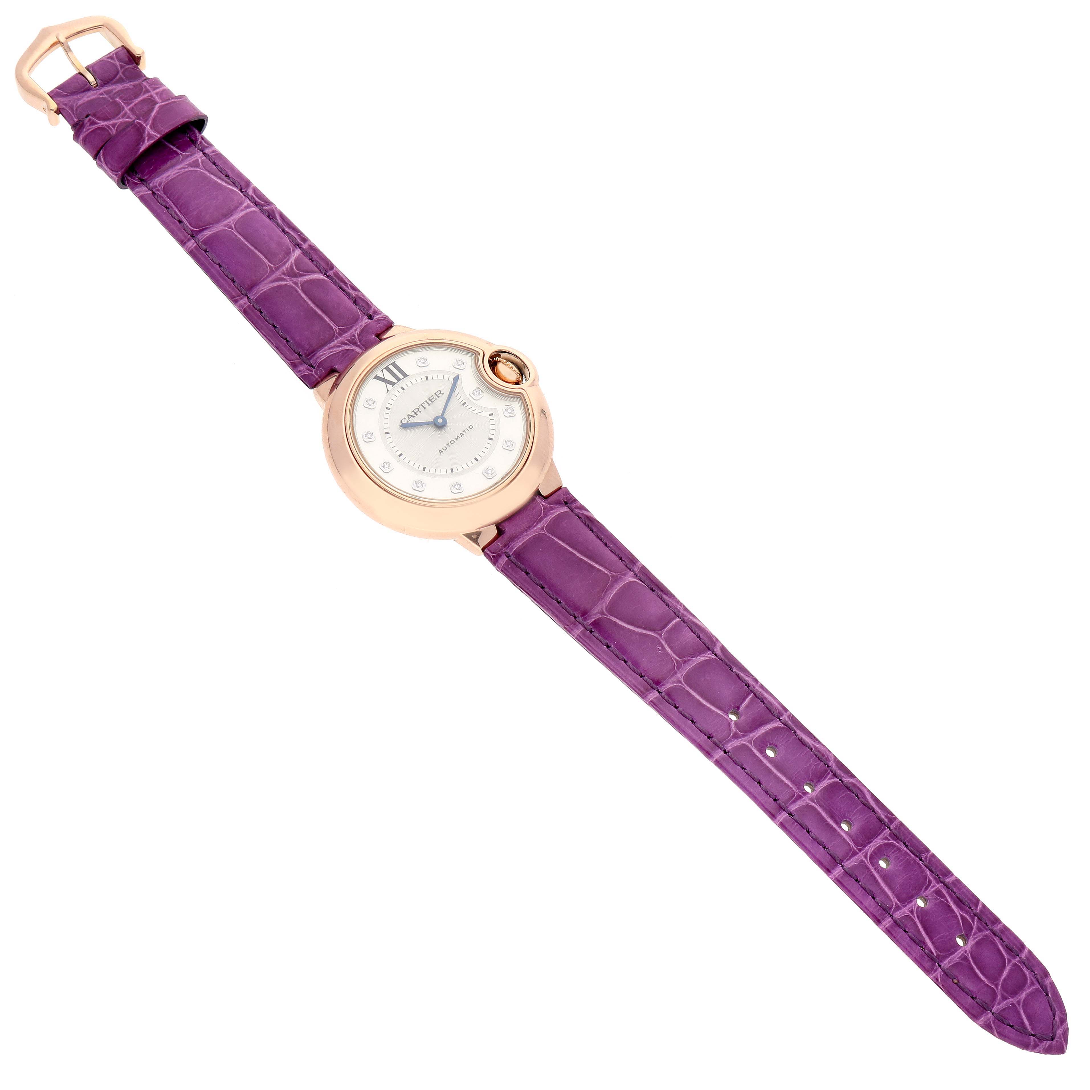 The Cartier Ballon Bleu WE902063 Women
s Rose Gold Silver Dial WE902063 Women
s Rose Gold Silver Dial watch is shown from a top-down angle displaying the entire purple strap, case, and dial.