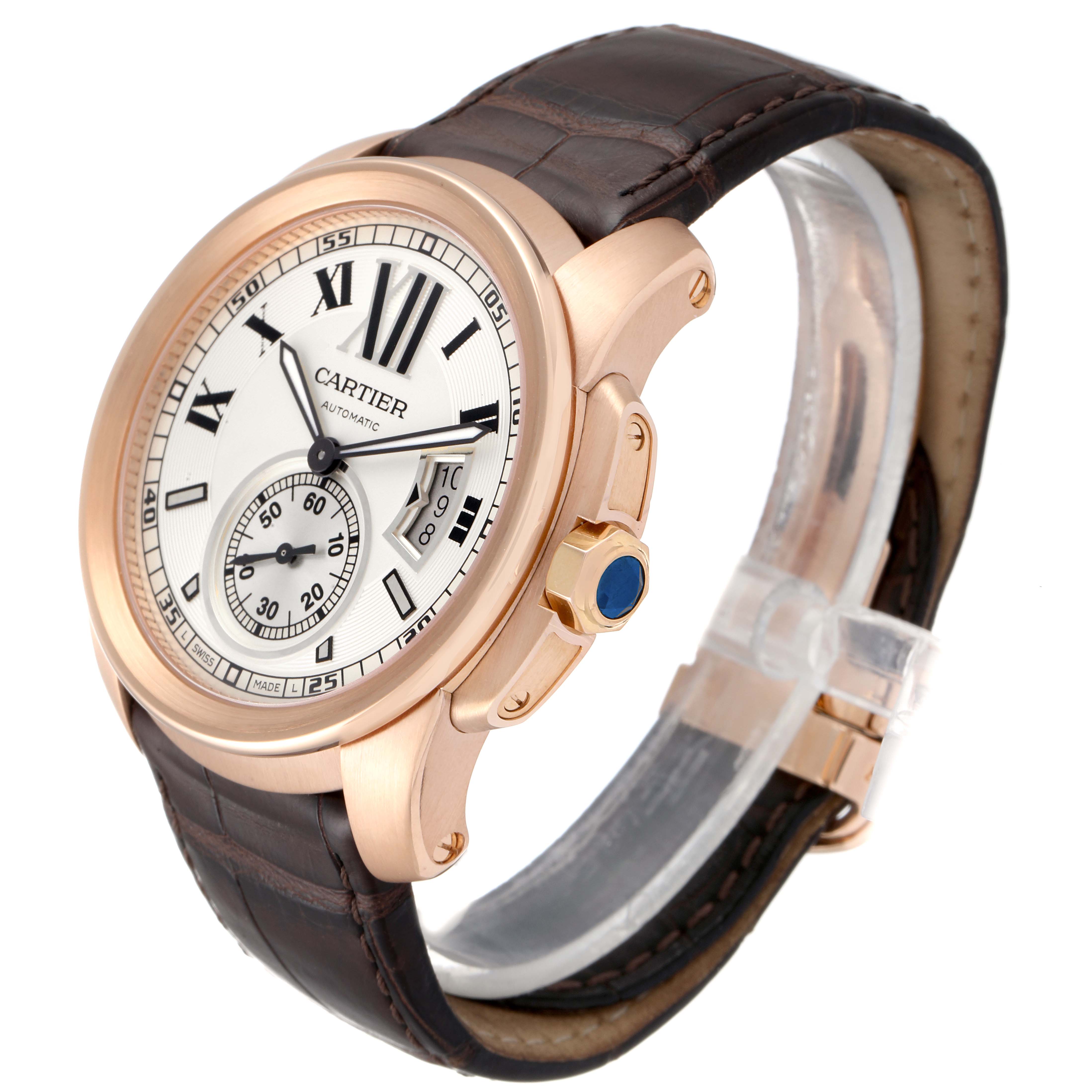 The image shows a Calibre de Cartier watch by Cartier at an angle displaying the dial, crown, and leather strap.
