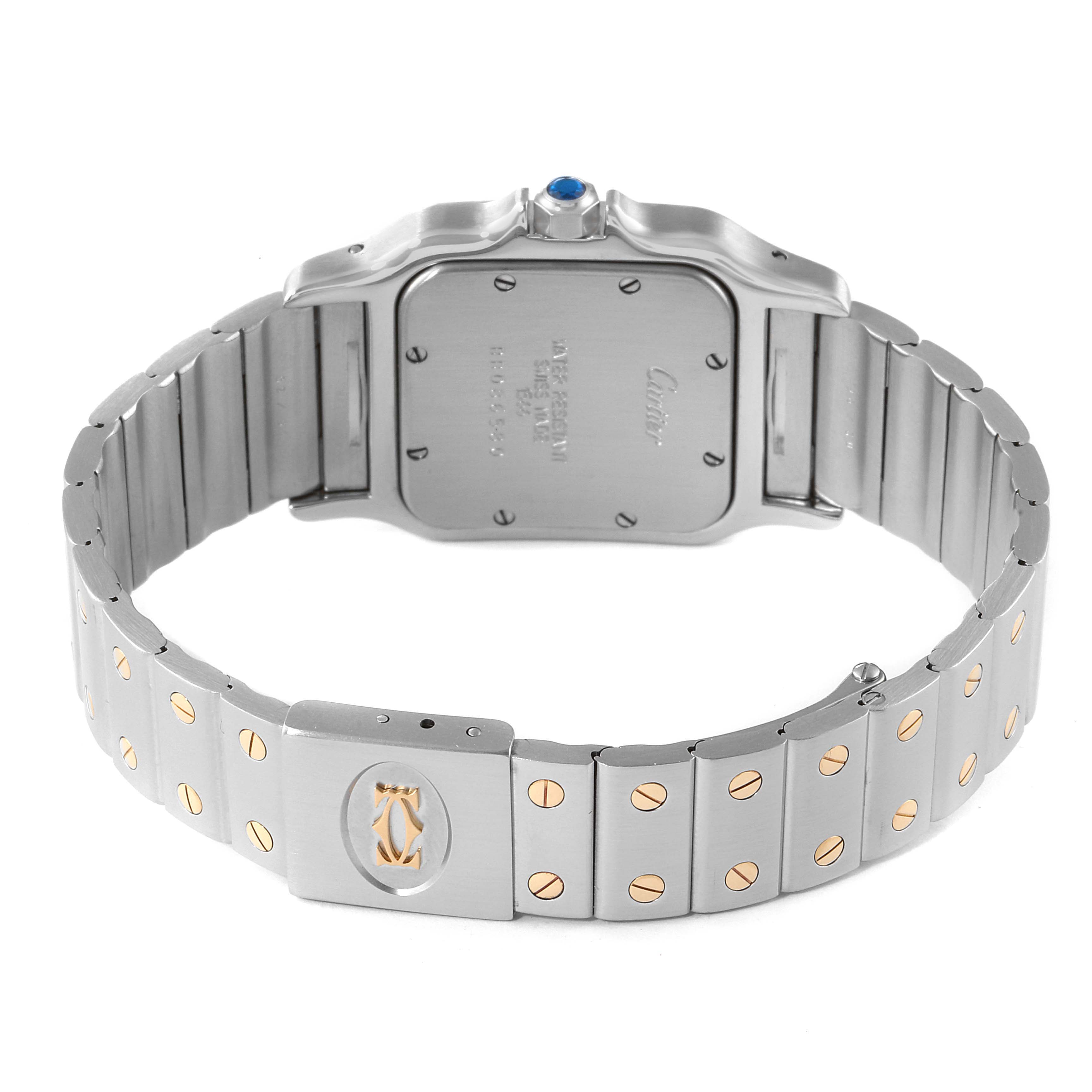 The image shows the back and bracelet of a Santos model by Cartier, featuring a brushed metal finish and screw accents.