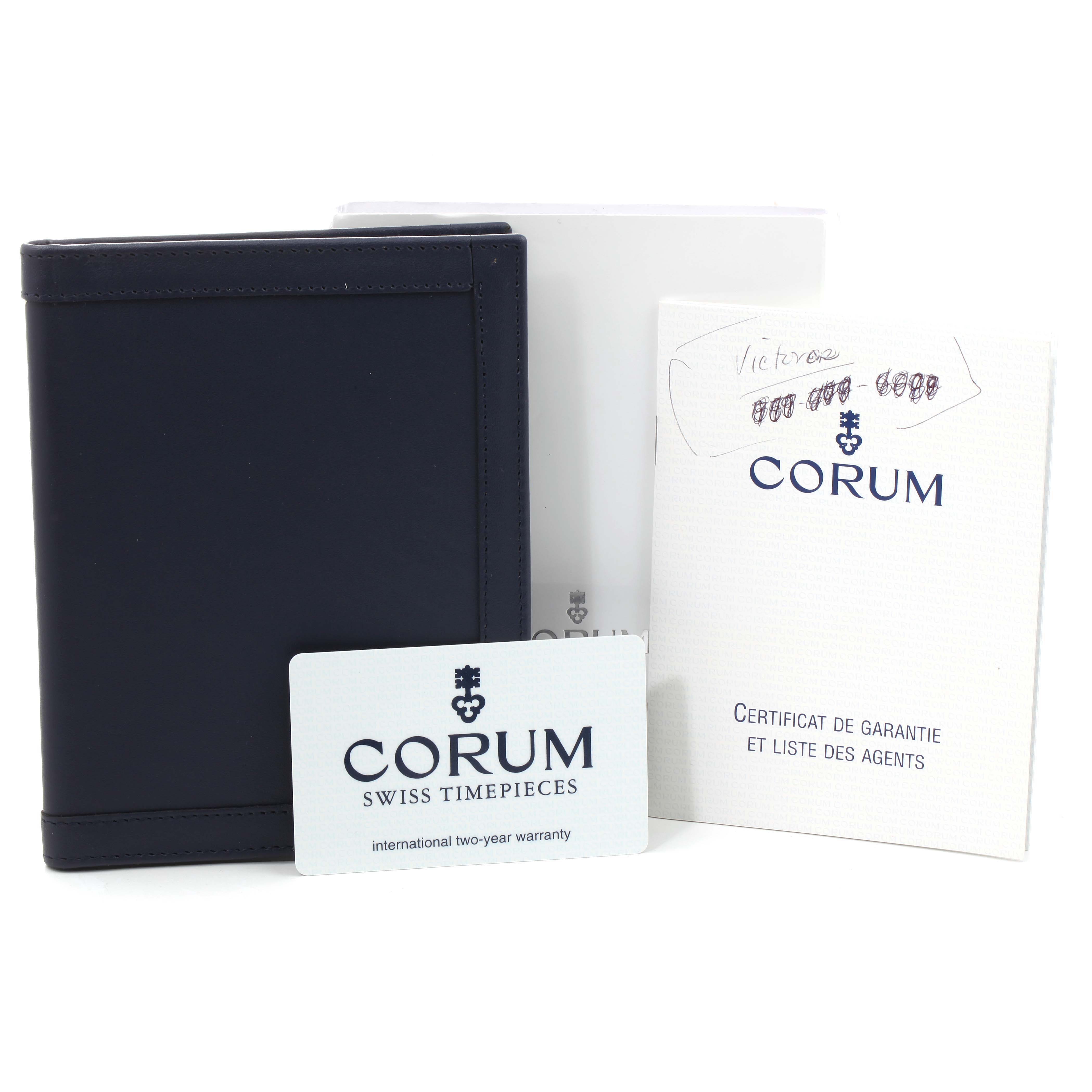 The image shows accessories for a Corum Coin Watch 1875  Men's Yellow Gold Black Dial 1875  Men's Yellow Gold Black Dial model, including a box, warranty card, and certificates.