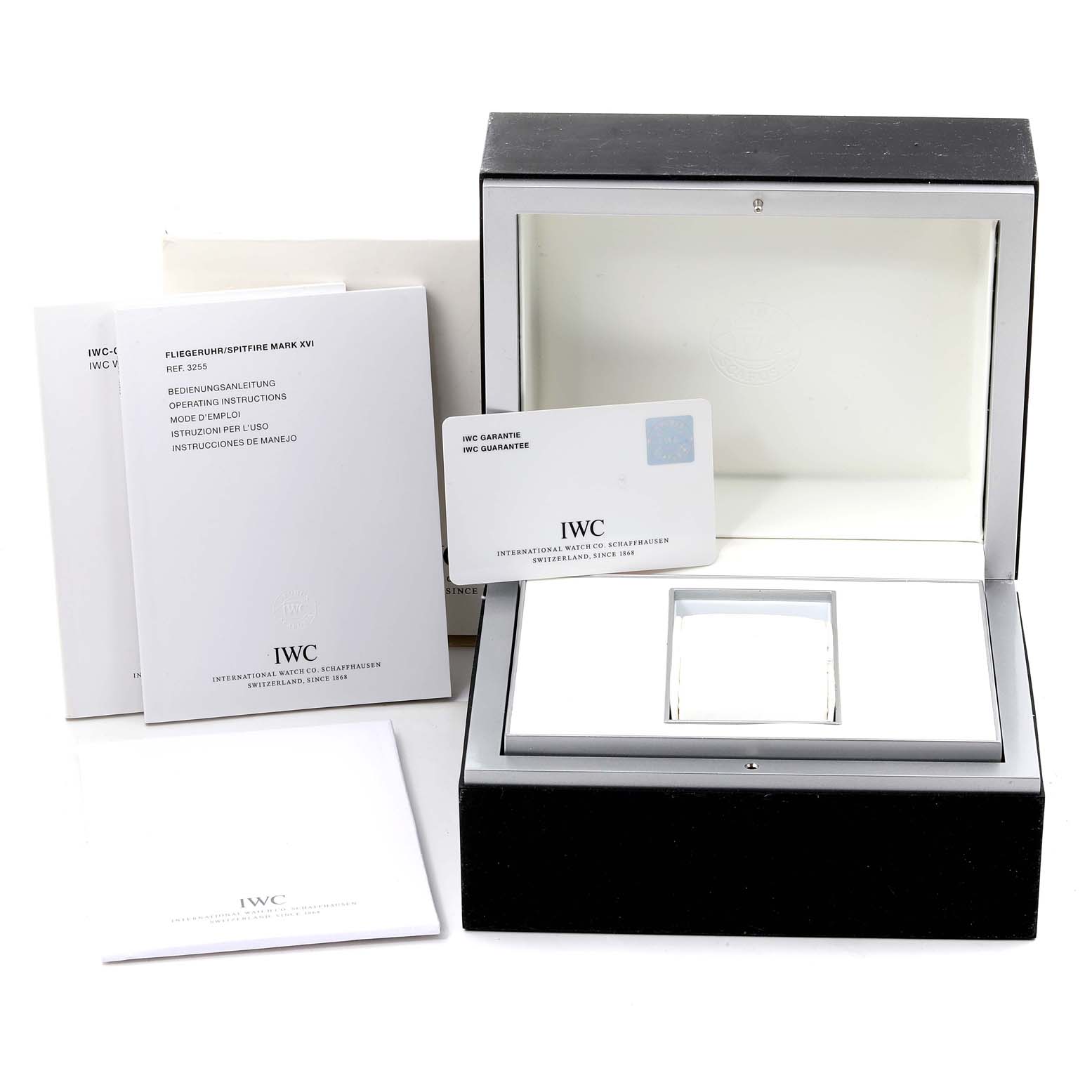 The image shows the packaging, manuals, and warranty card of the Pilot model by IWC, with the watch box open.