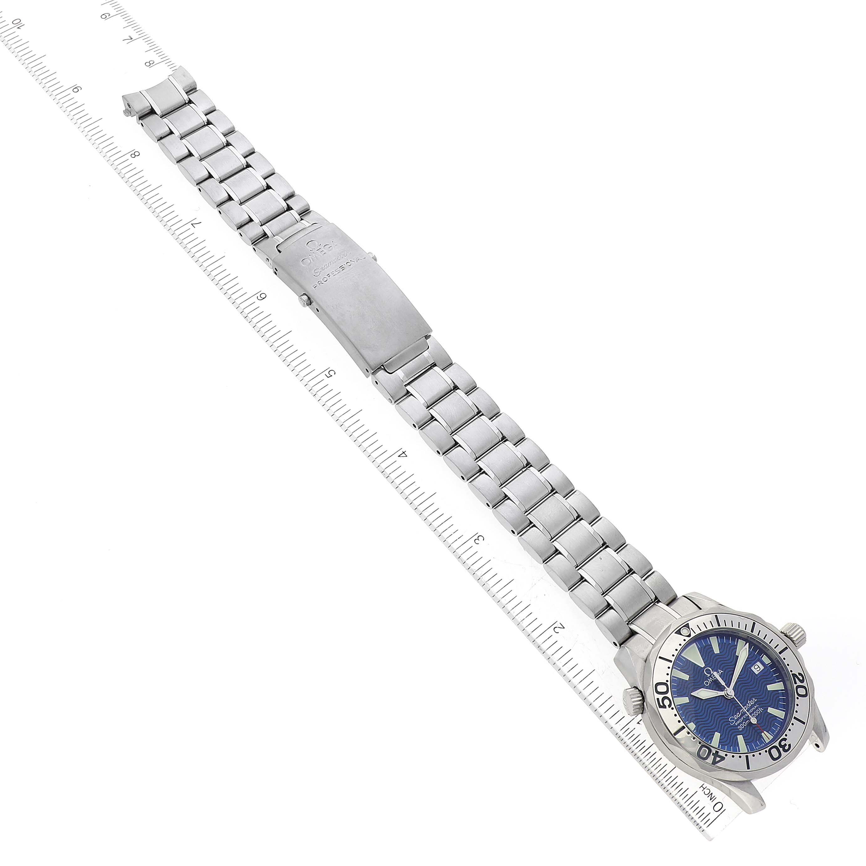 The image shows an Omega Seamaster 2263.80.00 Men
s Stainless Steel Blue Dial 2263.80.00 Men
s Stainless Steel Blue Dial watch laid flat with a ruler beside it, displaying the band and watch face from a top-down angle.