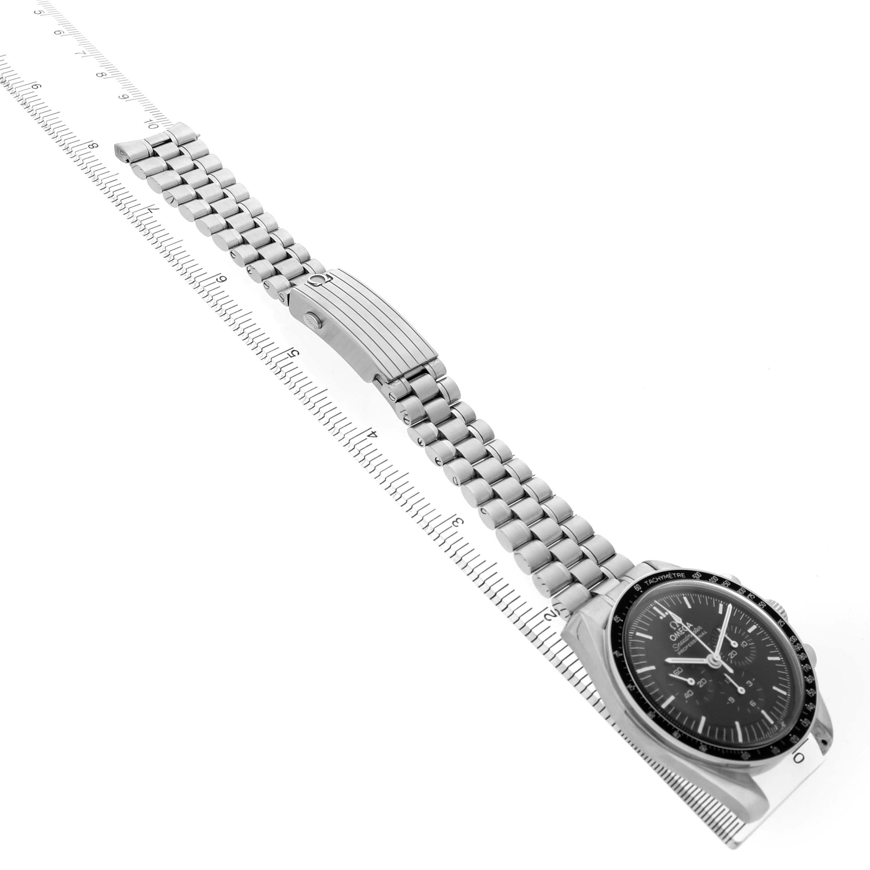 The Omega Speedmaster 310.30.42.50.01.001 Men's Stainless Steel Black Dial watch is shown from a side angle, featuring the dial, bezel, and metal bracelet laid next to a ruler.