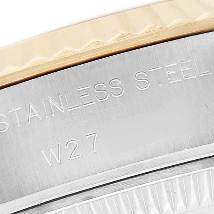 The image shows a close-up of the edge of a Rolex Datejust 69173 Women's Steel and Gold (two tone) Champagne Dial watch, highlighting the stainless steel part with engraved text.