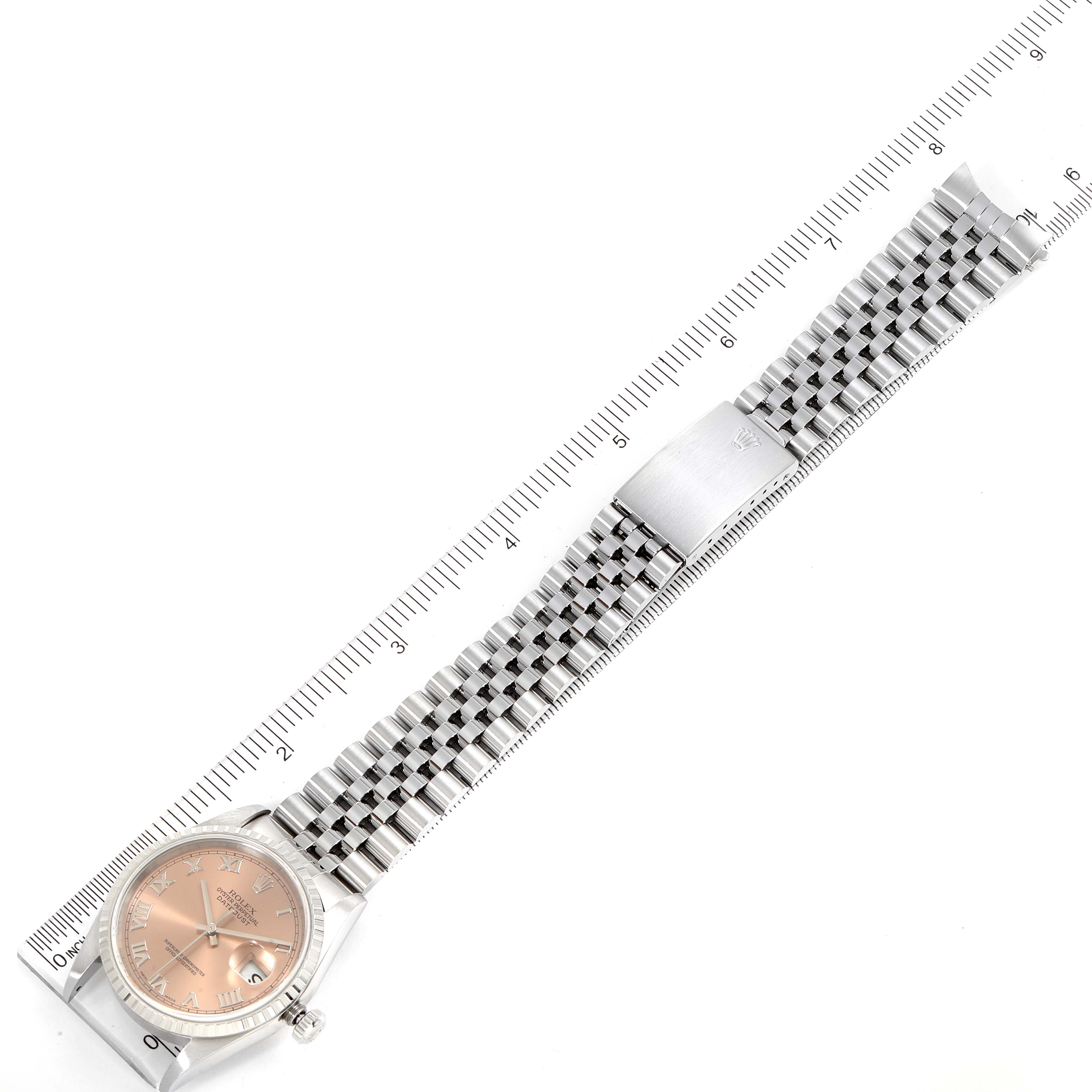 The image shows a Rolex Datejust 16220 Men
s Stainless Steel Pink Dial 16220 Men
s Stainless Steel Pink Dial watch laid flat, displaying the dial, bracelet, and clasp, along with a measuring ruler.