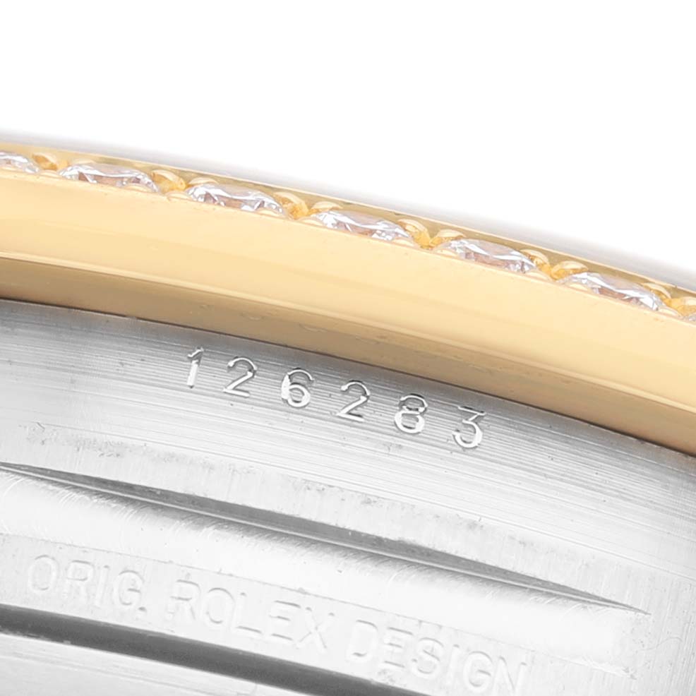 The image shows a close-up of the bezel with diamonds and part of the case of a Rolex Datejust 126283 Men's Steel and Gold (two tone) White Dial watch, including engravings.