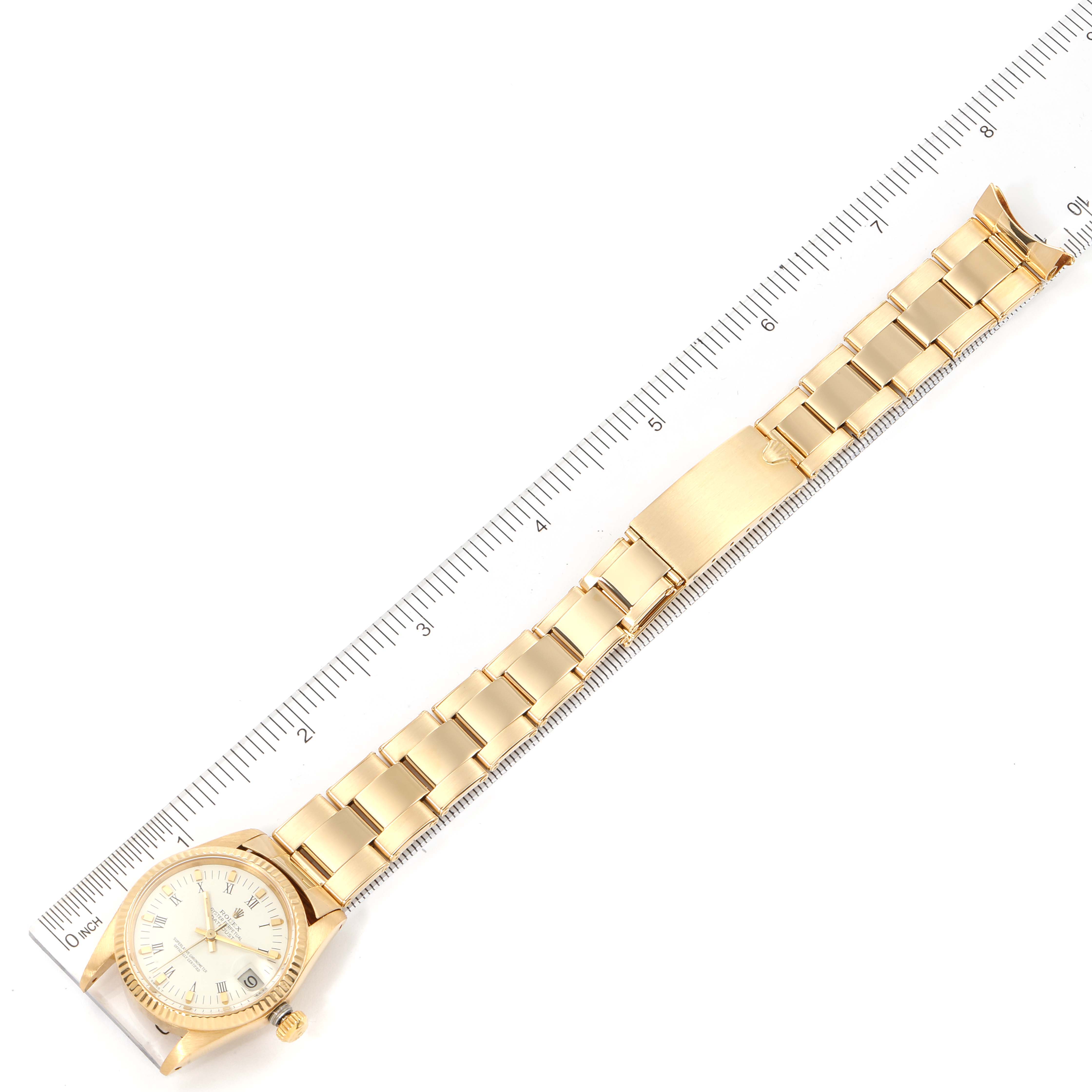 The image shows a Rolex President 6827 Women's Yellow Gold White Dial 6827 Women's Yellow Gold White Dial model watch, displaying its face, bezel, crown, and bracelet laid next to a ruler.
