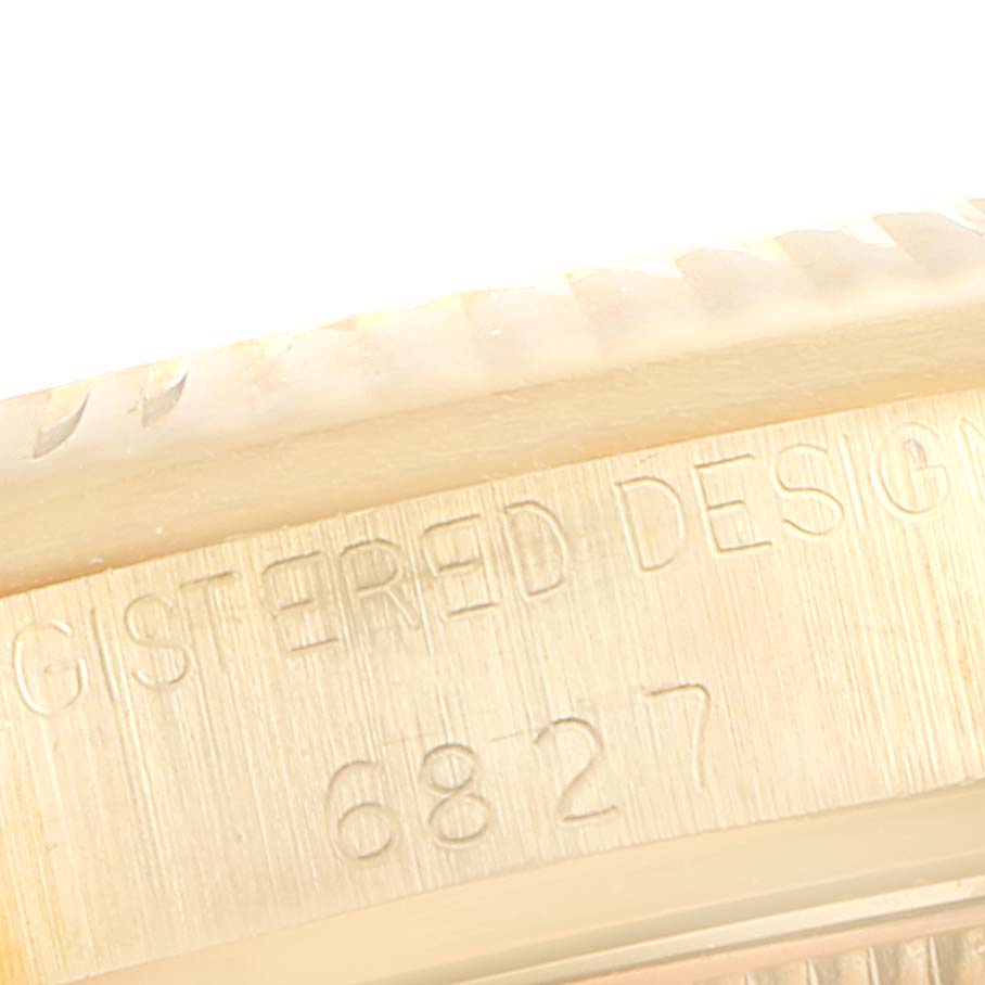 This image shows a close-up of the side of the Rolex President 6827 Women's Yellow Gold White Dial 6827 Women's Yellow Gold White Dial model watch, featuring engraved text and the edge of the bezel.