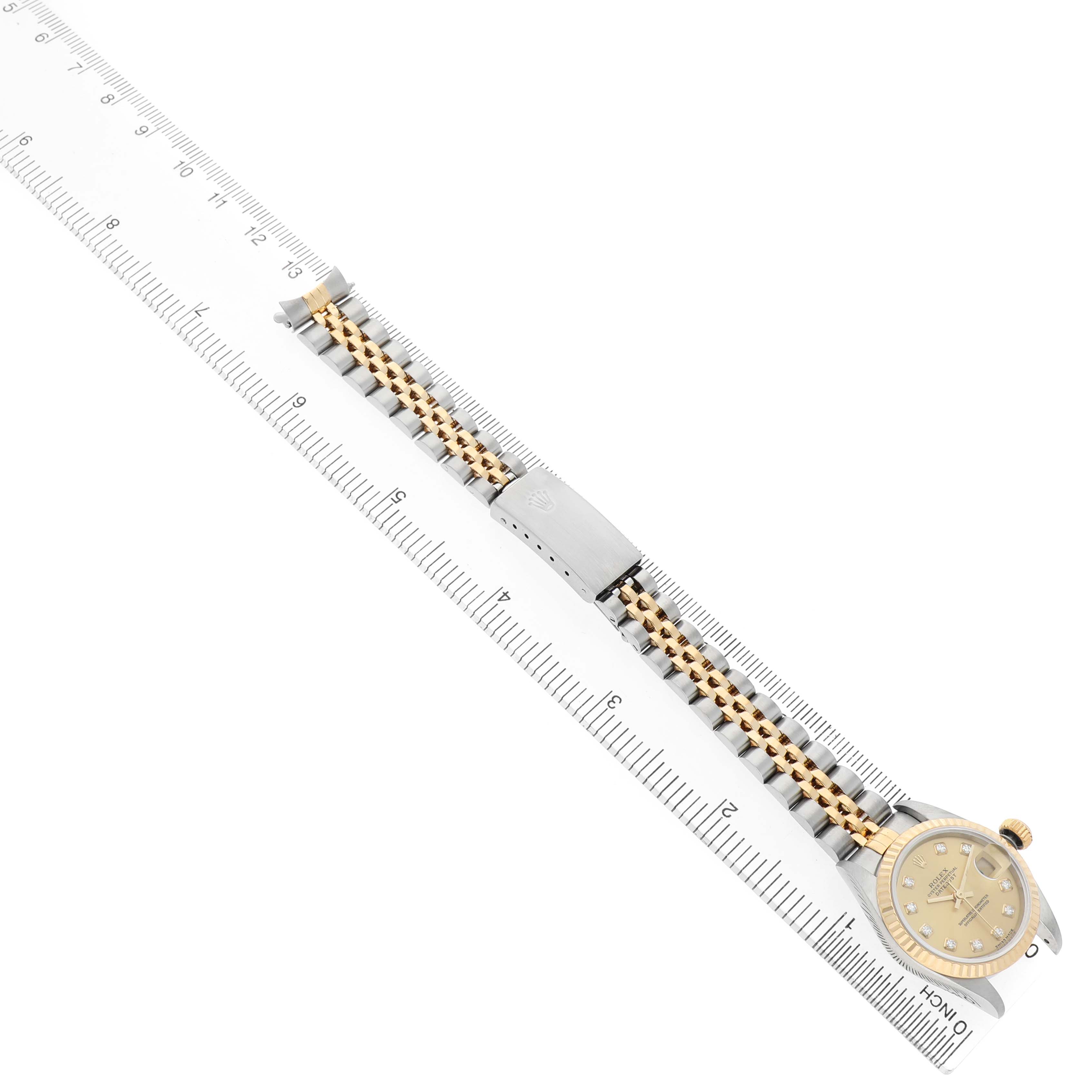 The Rolex Datejust 79173 Women's Steel and Gold (two tone) Champagne Dial watch is shown from an aerial angle with the bracelet extended alongside a ruler for scale.