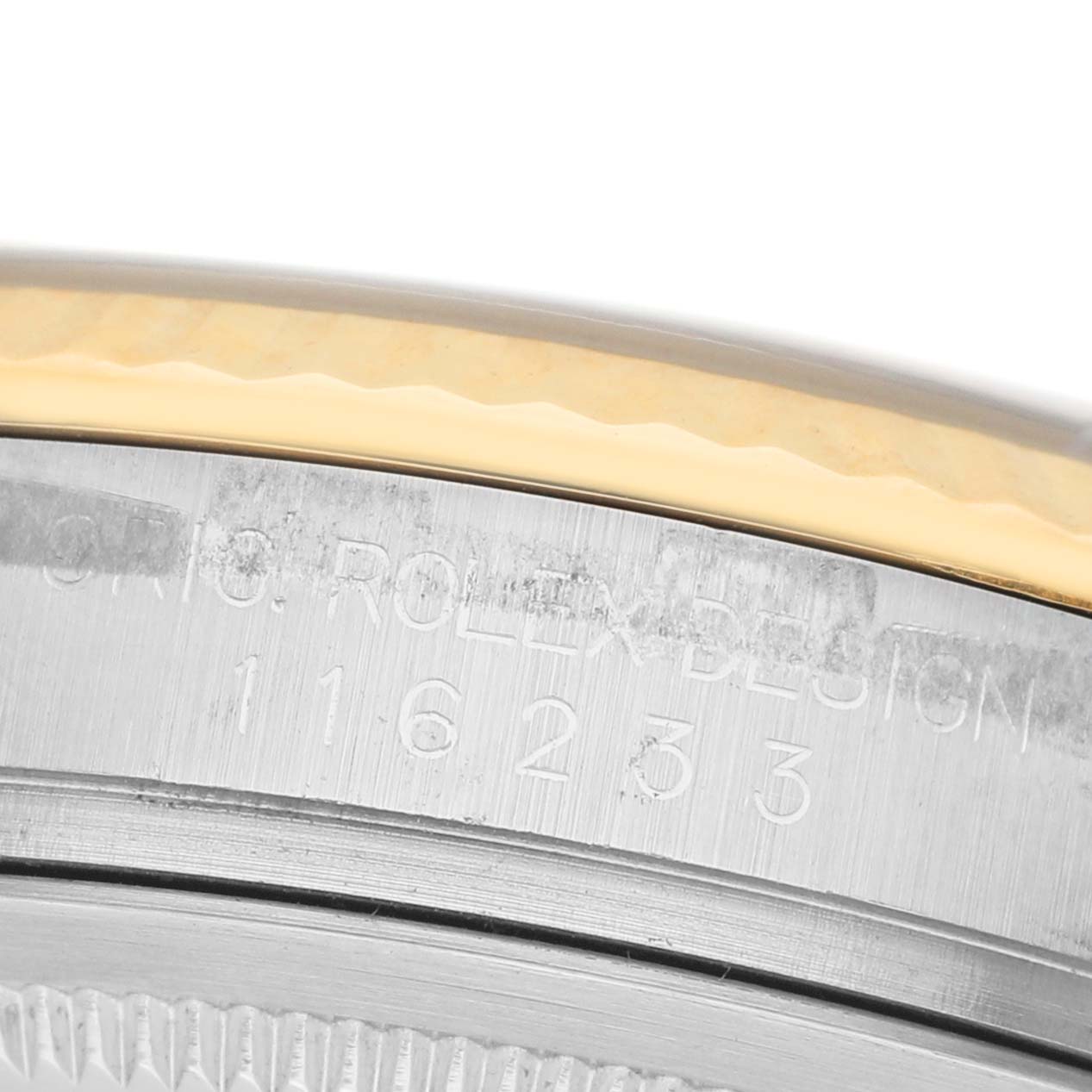 The image shows the case side of a Rolex Datejust 116233 Women's Steel and Gold (two tone) Champagne Dial, featuring engraved details and part of the bezel.