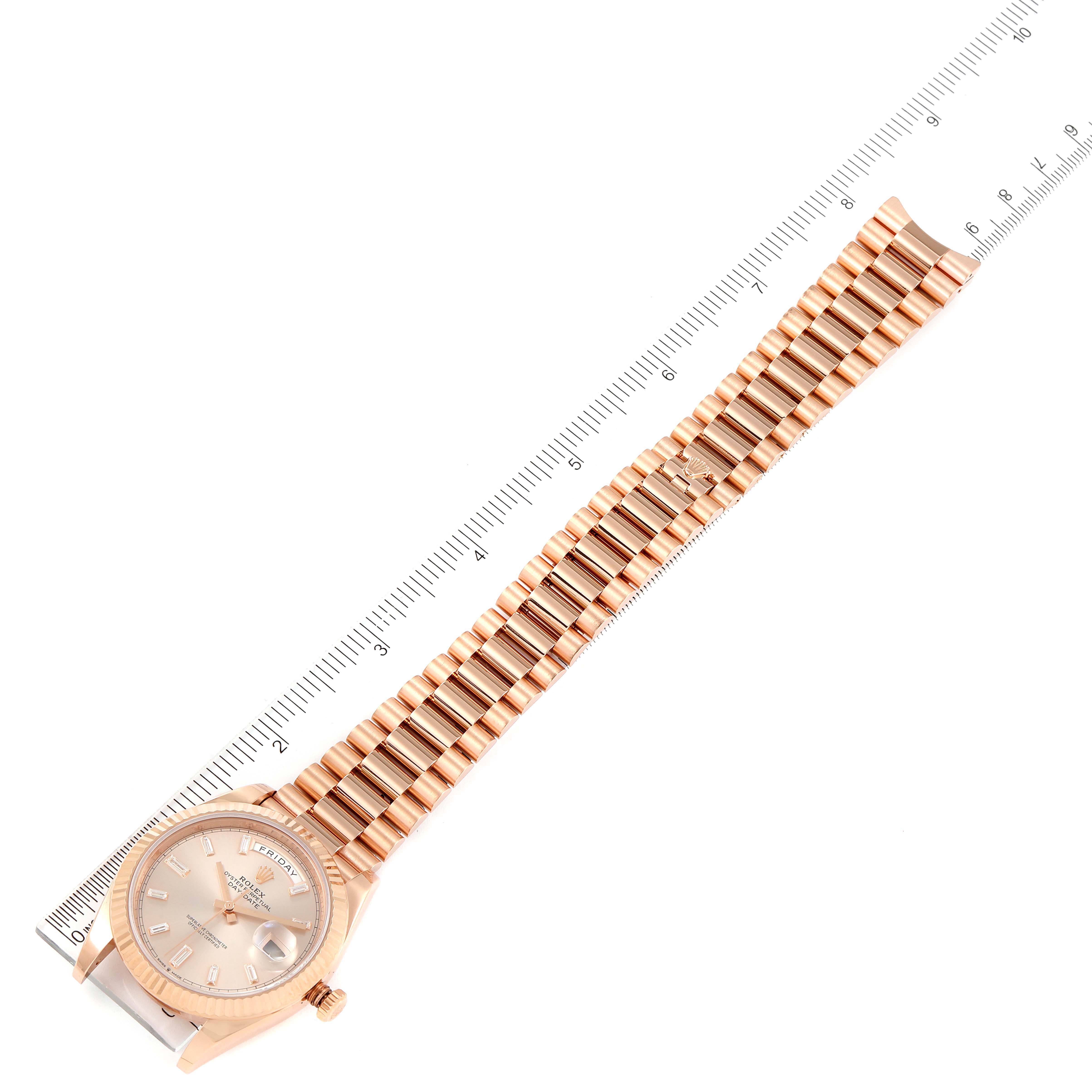 The Rolex President 228235 Men's Rose Gold Pink Dial 228235 Men's Rose Gold Pink Dial model watch is shown laid flat with its face, bracelet, and a ruler for size reference.