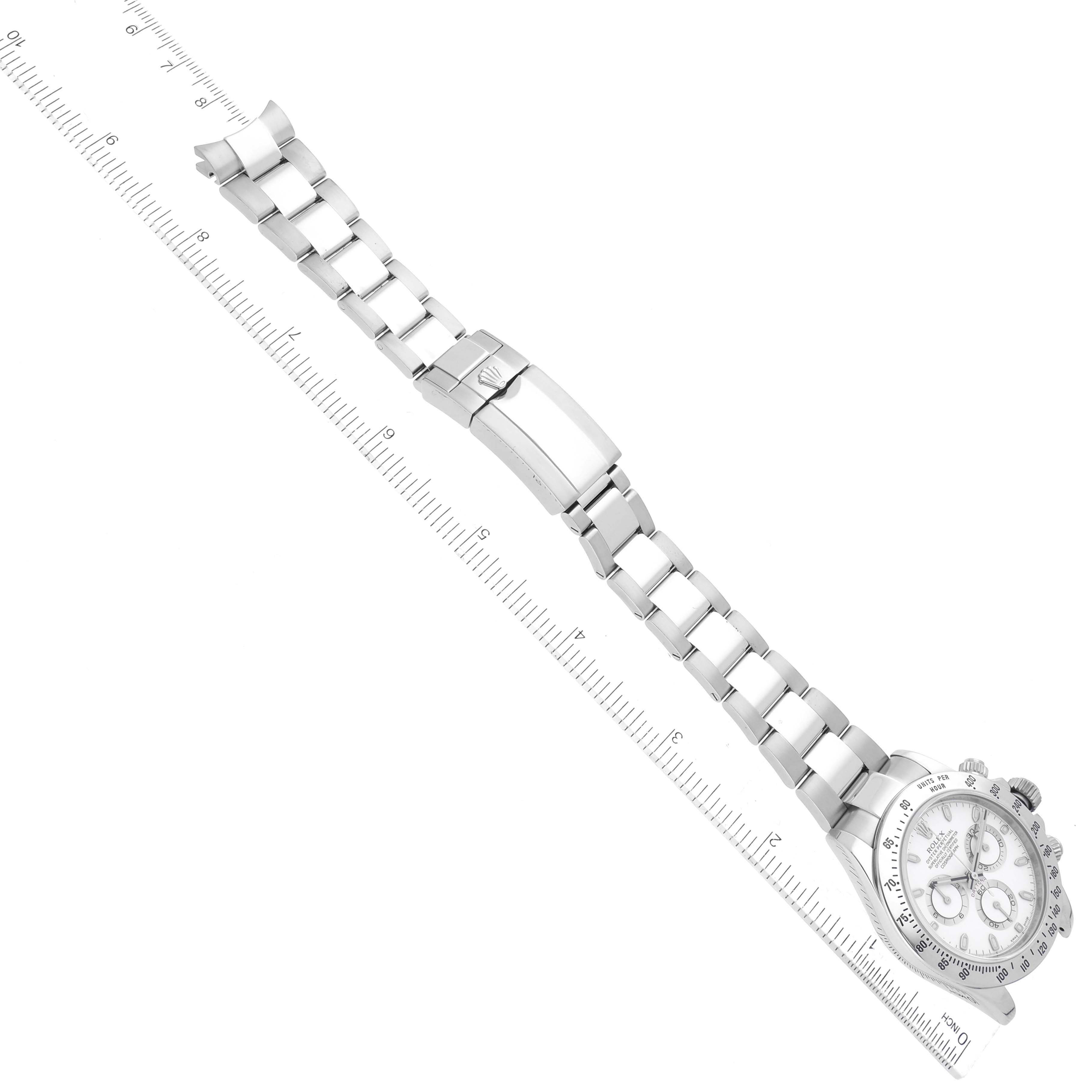 The image shows the Rolex Daytona 116520 Men's Stainless Steel White Dial 116520 Men's Stainless Steel White Dial watch laid flat with its full bracelet and clasp extended alongside a ruler for measuring.