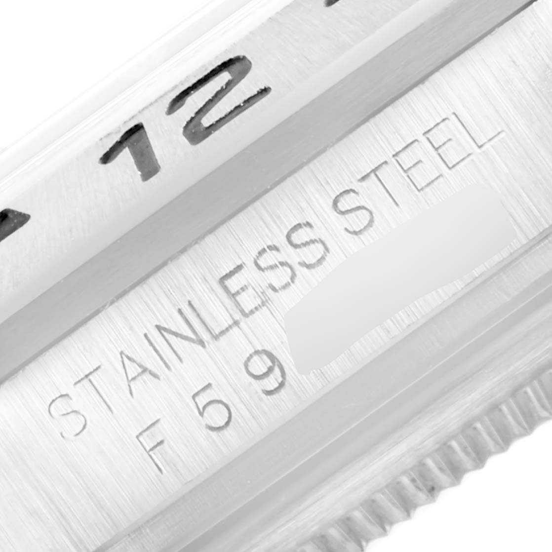 This close-up image of a Rolex Explorer 16570 Men's Stainless Steel White Dial 16570 Men's Stainless Steel White Dial watch shows part of the bezel and the inscription "STAINLESS STEEL" with serial numbers.