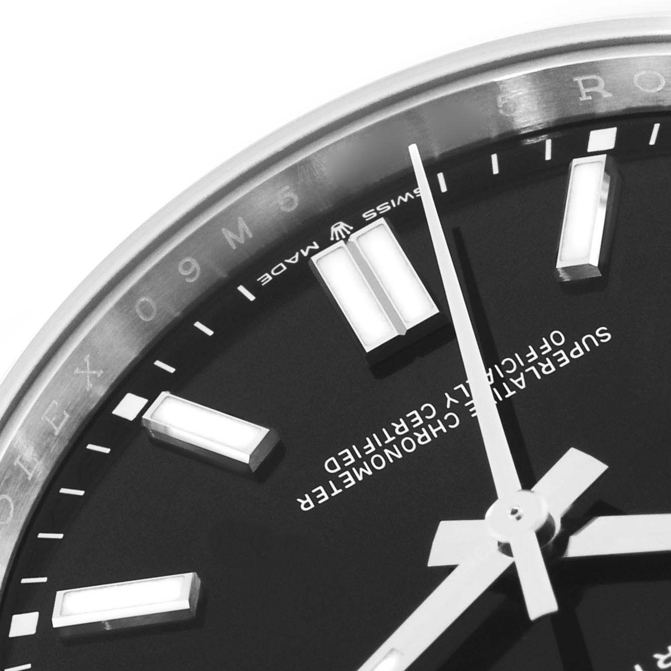 This close-up of a Rolex Oyster Perpetual 124300 Men
s Stainless Steel Black Dial 124300 Men
s Stainless Steel Black Dial watch shows part of the dial, hour markers, hands, and a portion of the bezel.