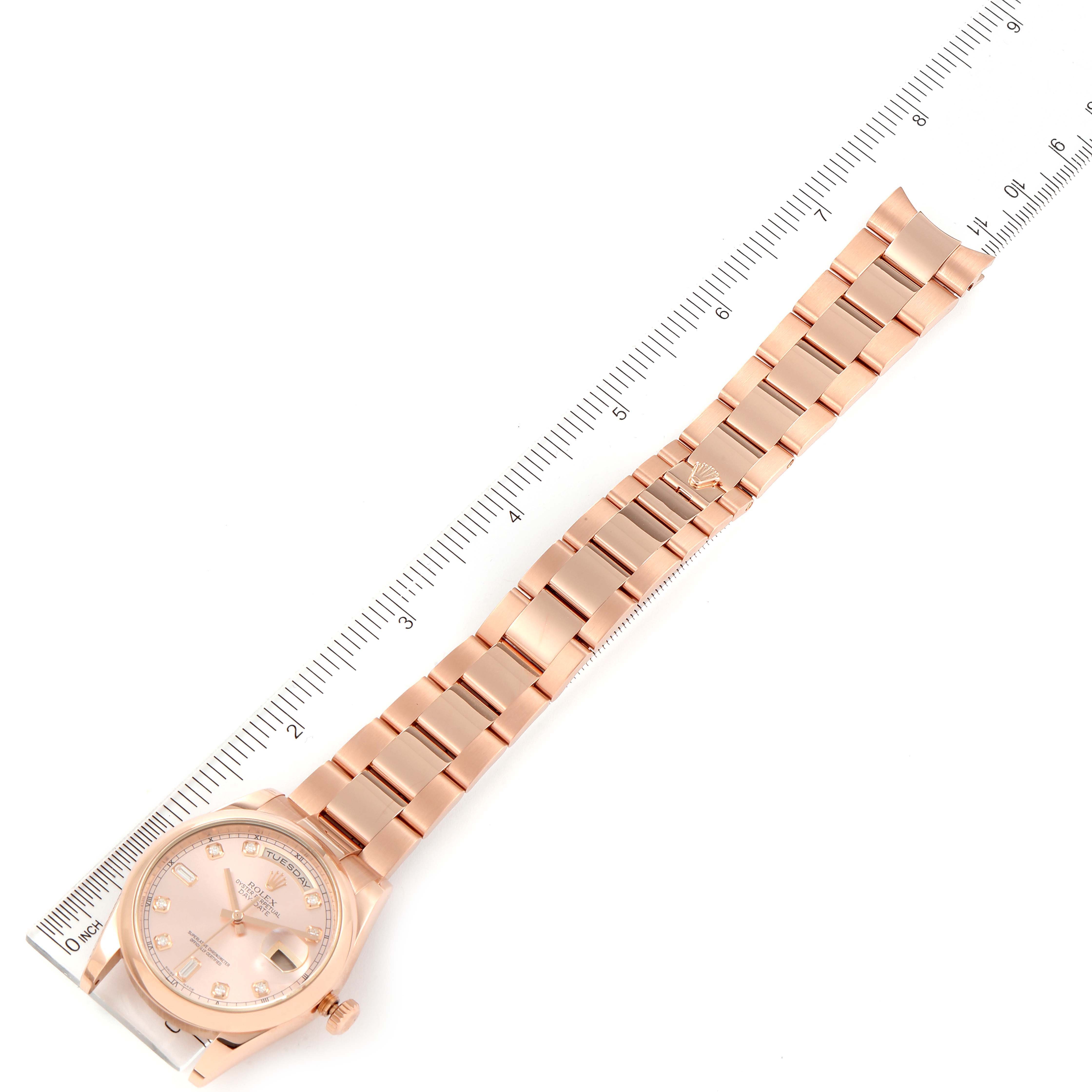 The image shows a President model by Rolex laid flat next to a ruler, displaying its face and full bracelet.