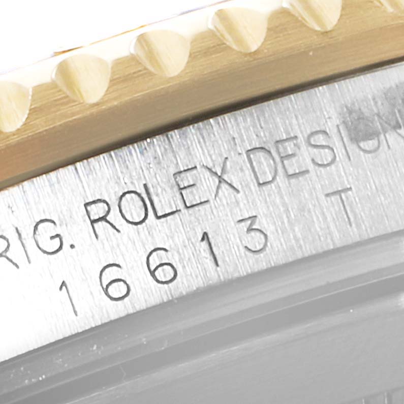 The image shows a close-up of the Rolex Submariner 16613 Men
s Steel and Gold (two tone) Blue Dial 16613 Men
s Steel and Gold (two tone) Blue Dial
s model number (16613) and the design engraving on the stainless steel case, along with part of the bezel.