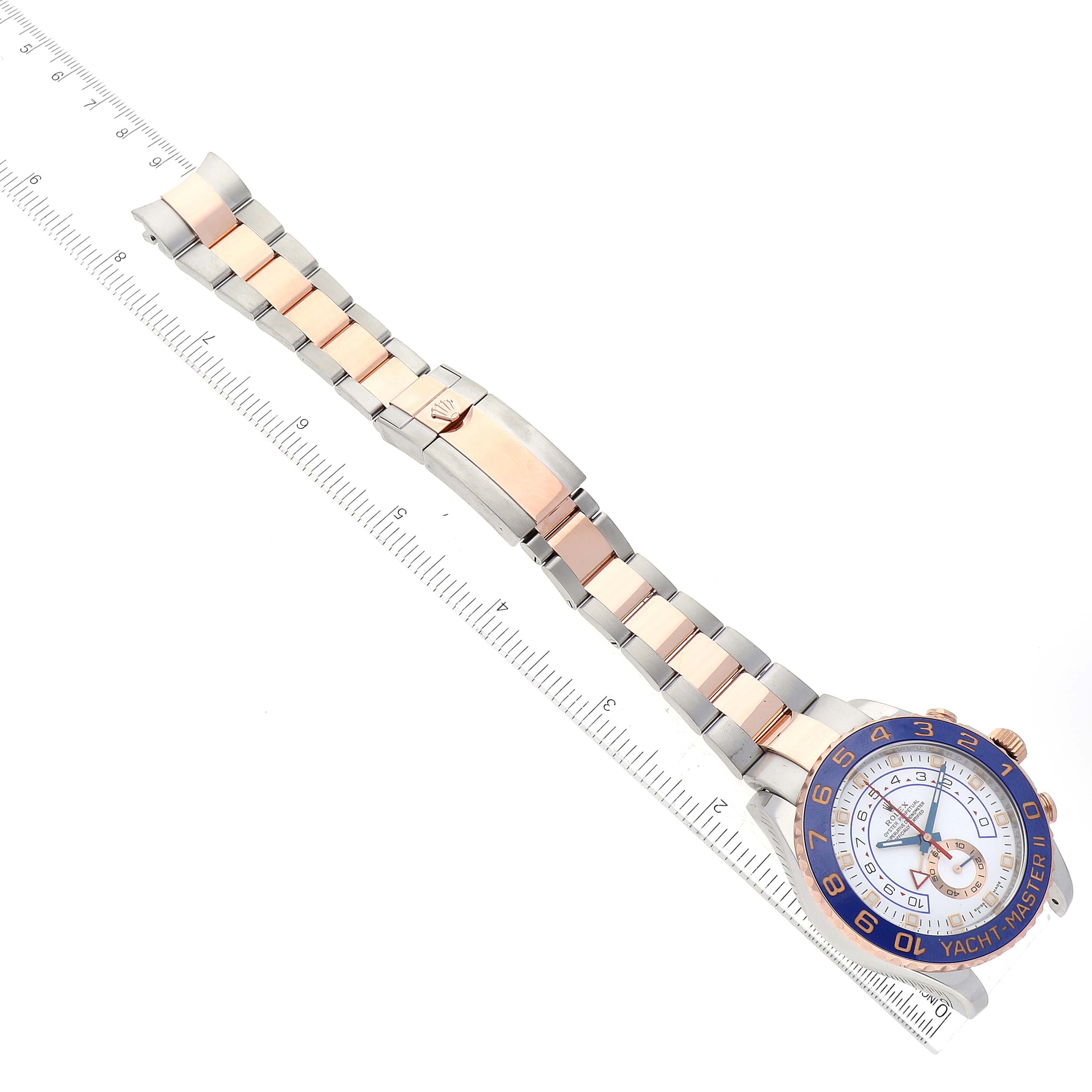 An aerial view of a Rolex Yacht-Master 116681 Men's Steel and Gold (two tone) White Dial 116681 Men's Steel and Gold (two tone) White Dial watch showing the face, bezel, and bracelet alongside a ruler.