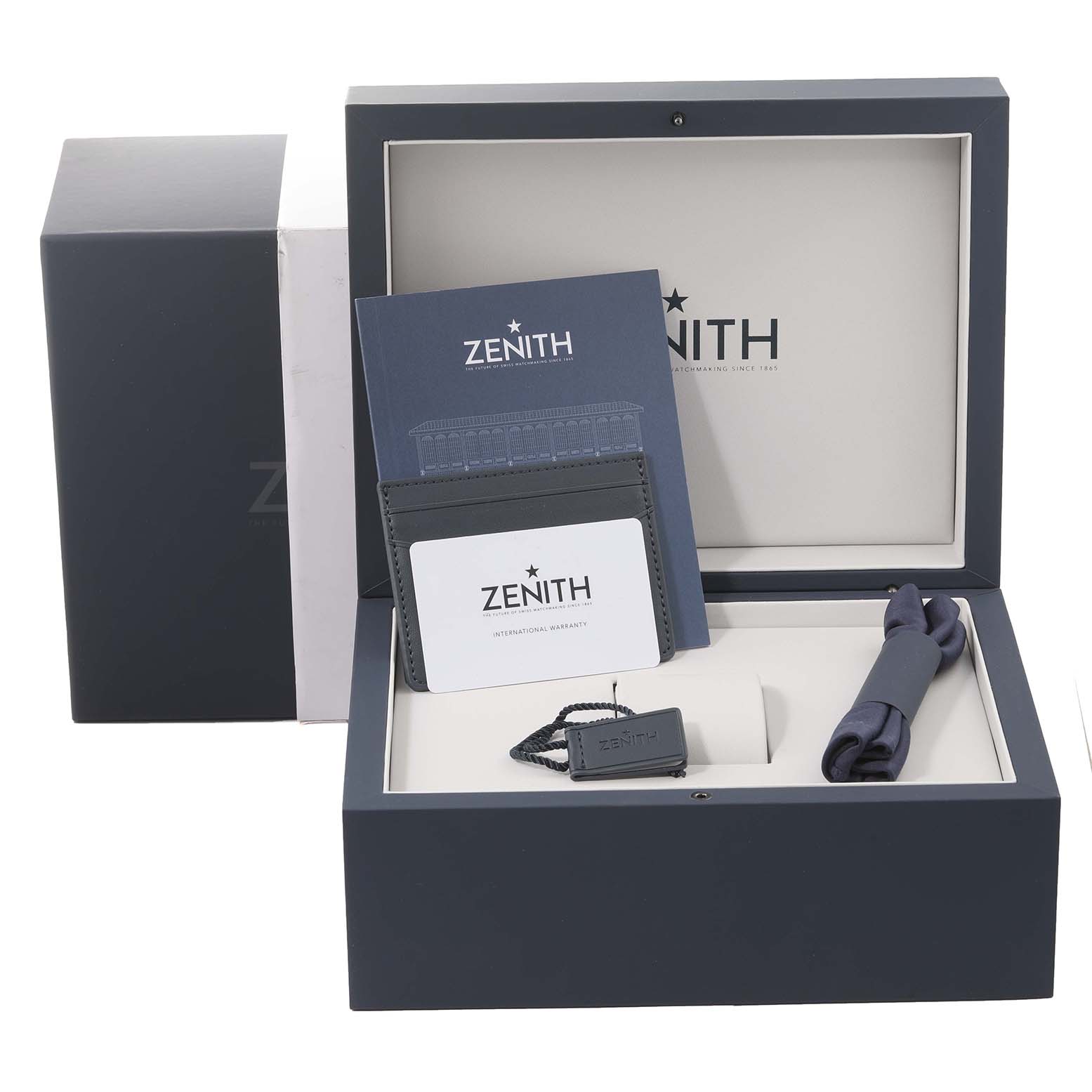 The image shows a Zenith Chronomaster 03.3100.3600/69.M3100 Men's Stainless Steel White Dial 03.3100.3600/69.M3100 Men's Stainless Steel White Dial watch box with user manuals, warranty card, and a cleaning cloth from a top-down angle.