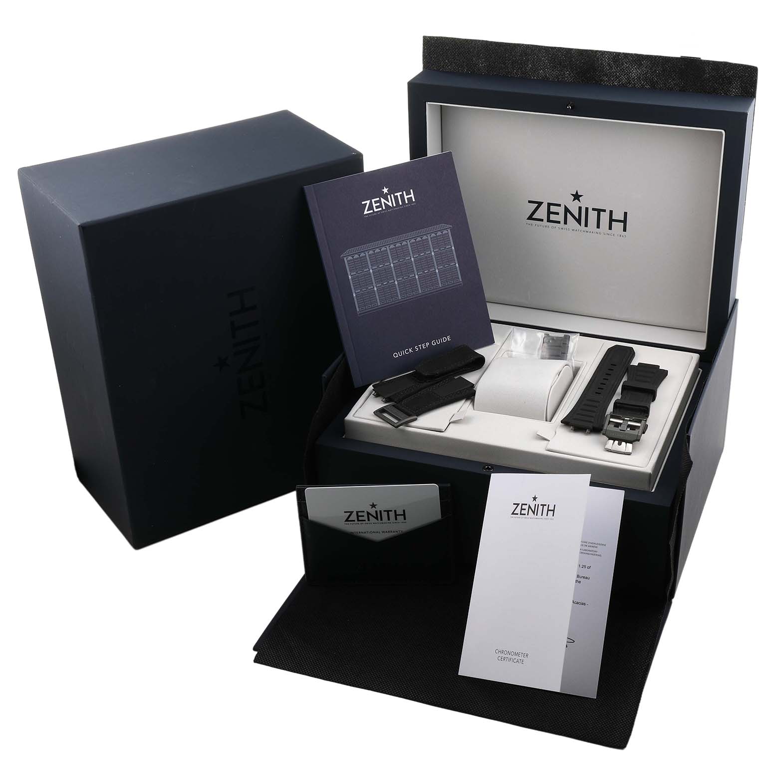 The image shows a Zenith Defy 97.9100.9004 Men's Titanium Grey Dial watch box containing manuals, an extra strap, and a watch case from an angled top view.