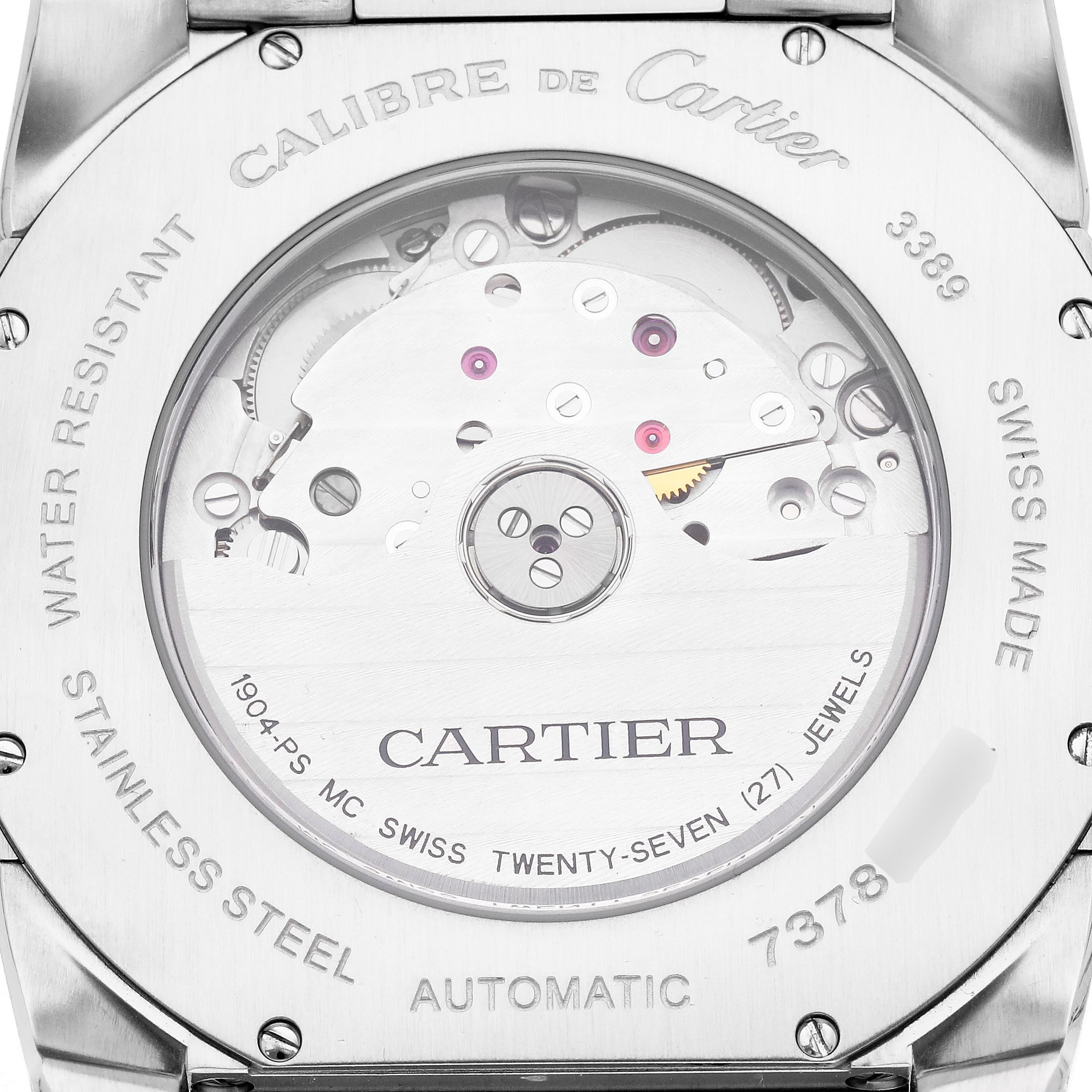 The image shows the back view of a Calibre de Cartier watch, revealing its automatic movement and engraved details.