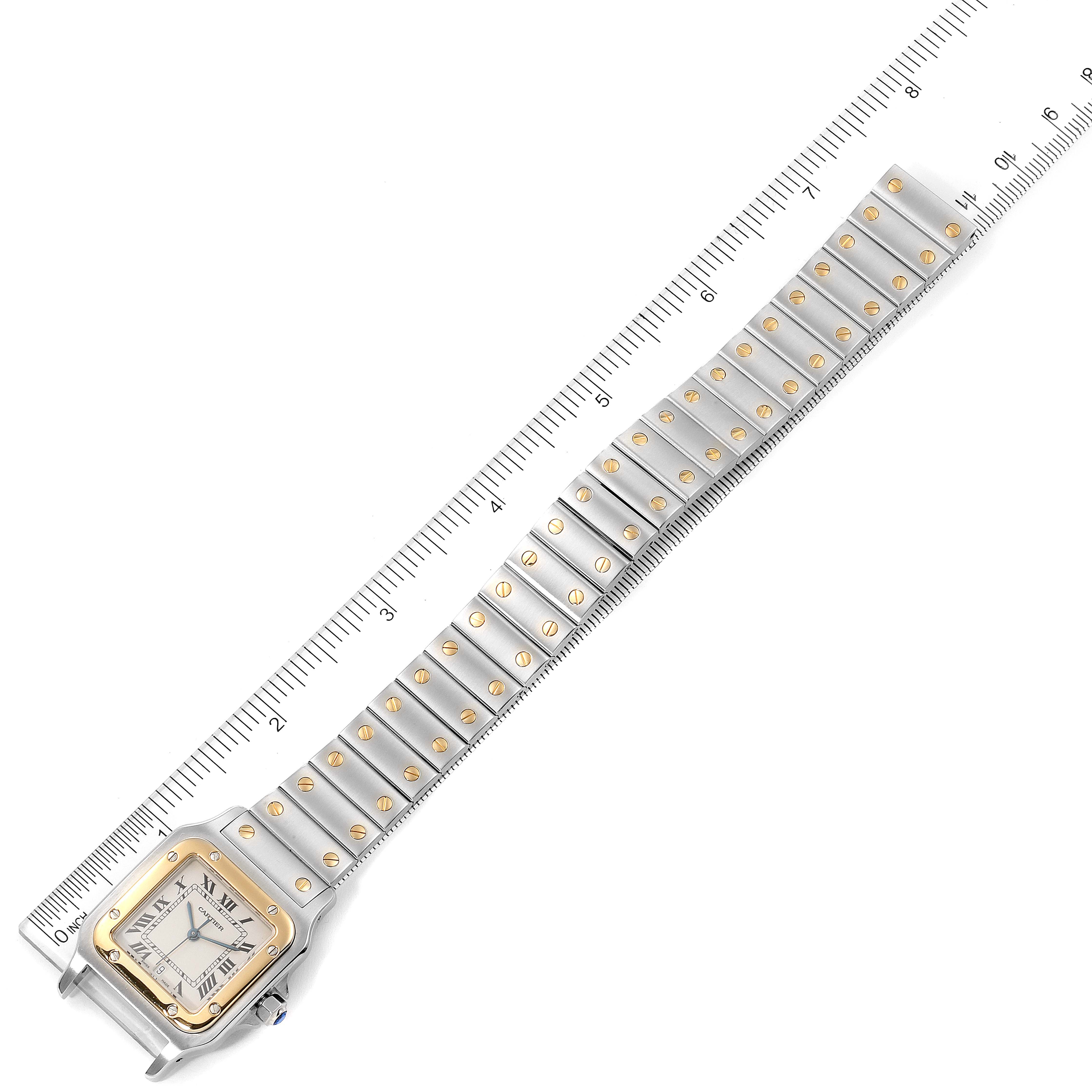 The Cartier Santos W20011C4 Men's Steel and Gold (two tone) Silver Dial W20011C4 Men's Steel and Gold (two tone) Silver Dial watch is shown from a top-down angle, highlighting the face and full bracelet with a ruler for scale.