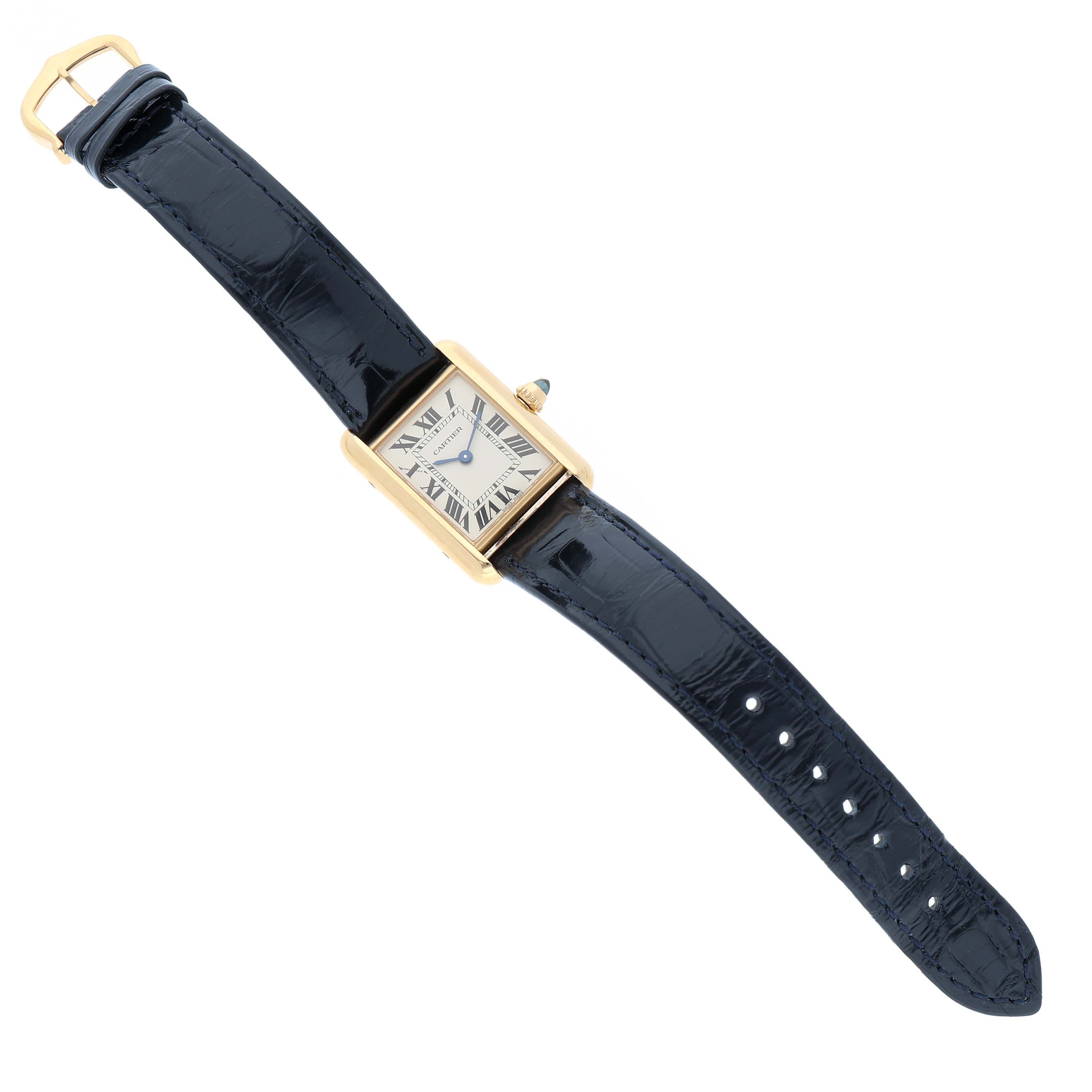 The Cartier Tank Louis WGTA0342 Women's Yellow Gold Silver Dial watch is shown from a top-down angle, displaying its face, leather strap, and gold casing.