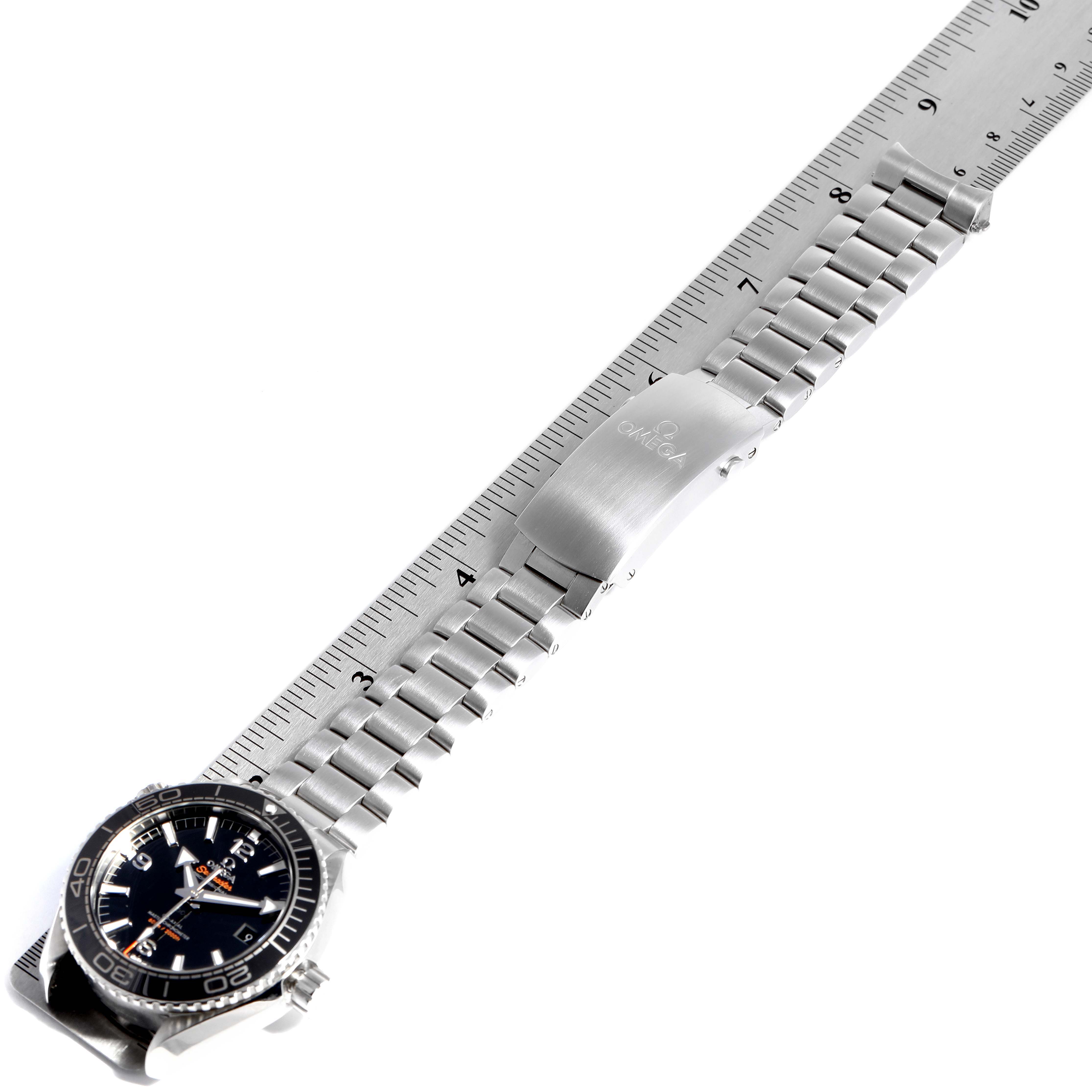 The image shows an Omega Planet Ocean 215.30.44.21.01.001 Men
s Stainless Steel Black Dial 215.30.44.21.01.001 Men
s Stainless Steel Black Dial watch laying flat with its stainless steel bracelet fully extended next to a ruler for measurement.