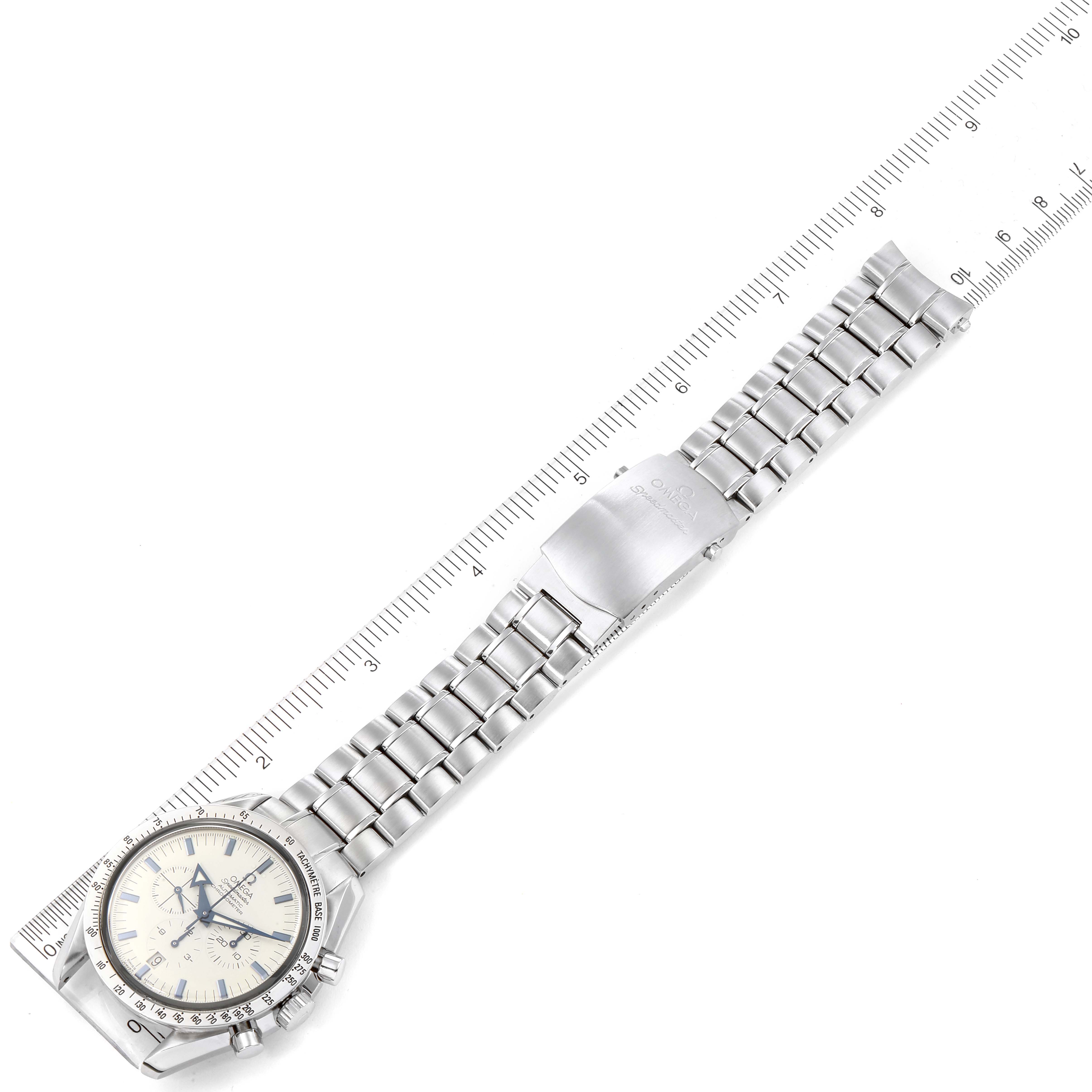 The image shows a top-down view of an Omega Speedmaster 3551.20.00 Men
s Stainless Steel White Dial 3551.20.00 Men
s Stainless Steel White Dial watch with its stainless steel bracelet extended alongside a ruler.
