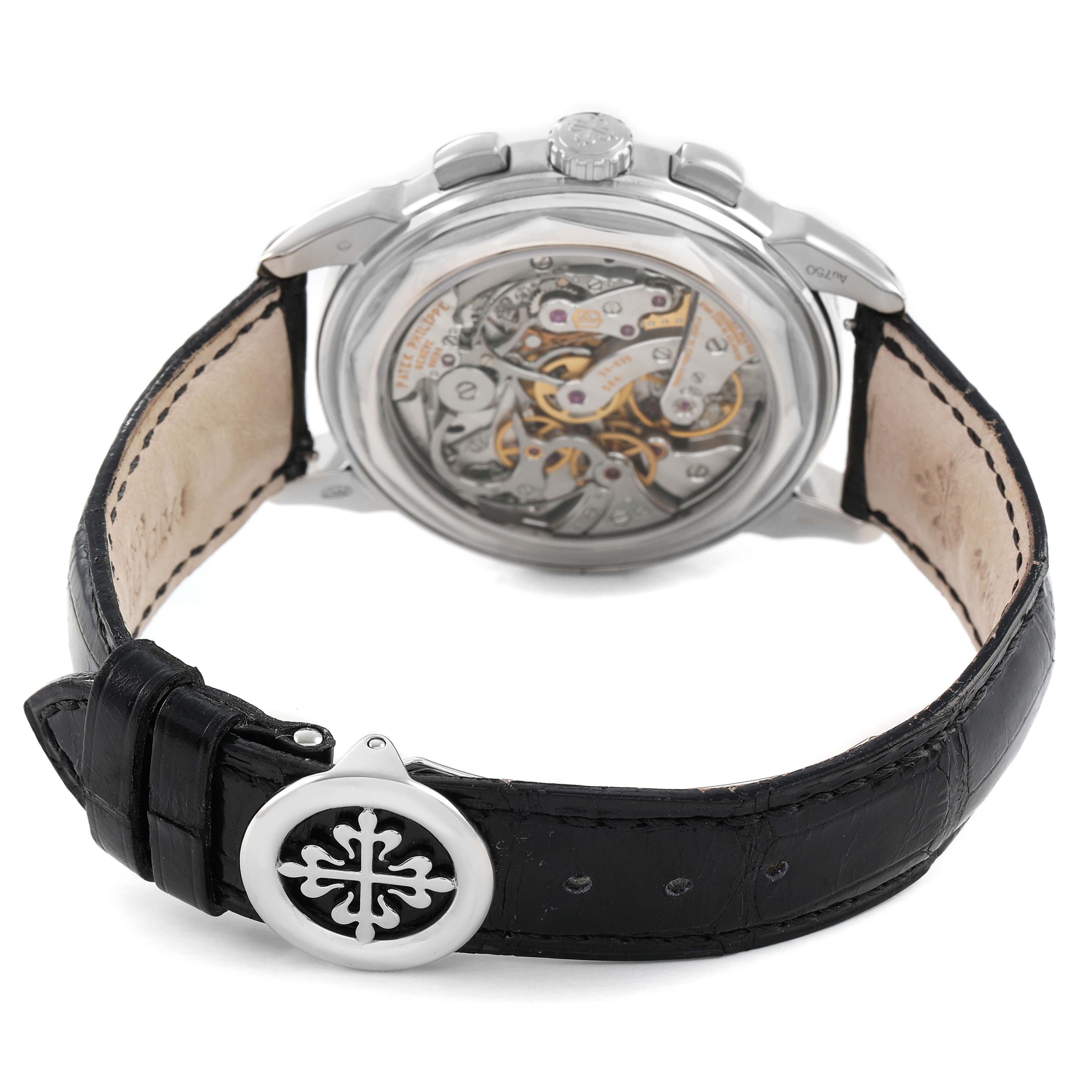 The Patek Philippe Complications 5270 Men's White Gold Silver Dial watch is shown from the back, highlighting its intricate movement and black leather strap with a clasp.