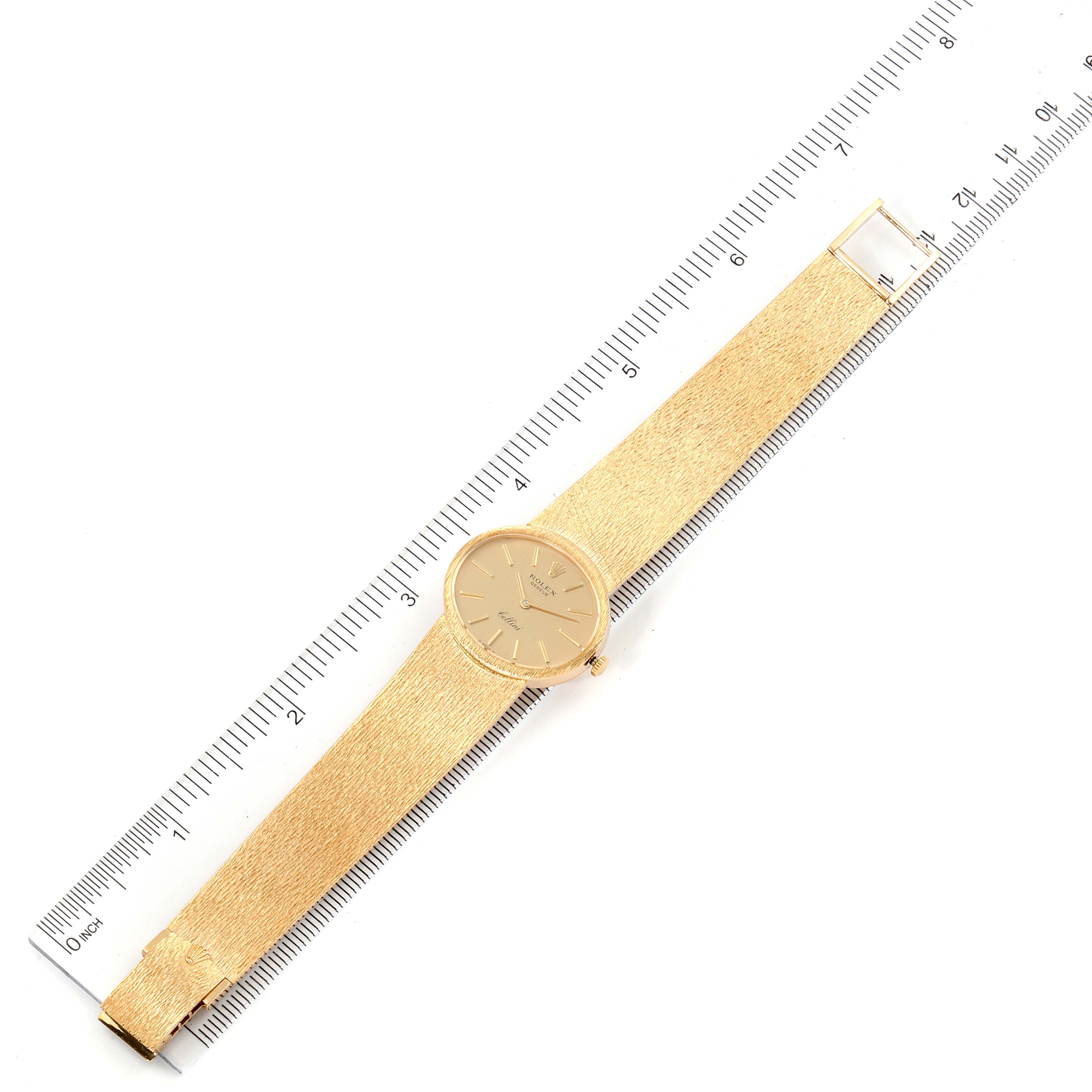 The Rolex Cellini  Women
s Yellow Gold Champagne Dial  Women
s Yellow Gold Champagne Dial watch is displayed flat with its golden dial and strap fully visible, alongside a ruler for scale.