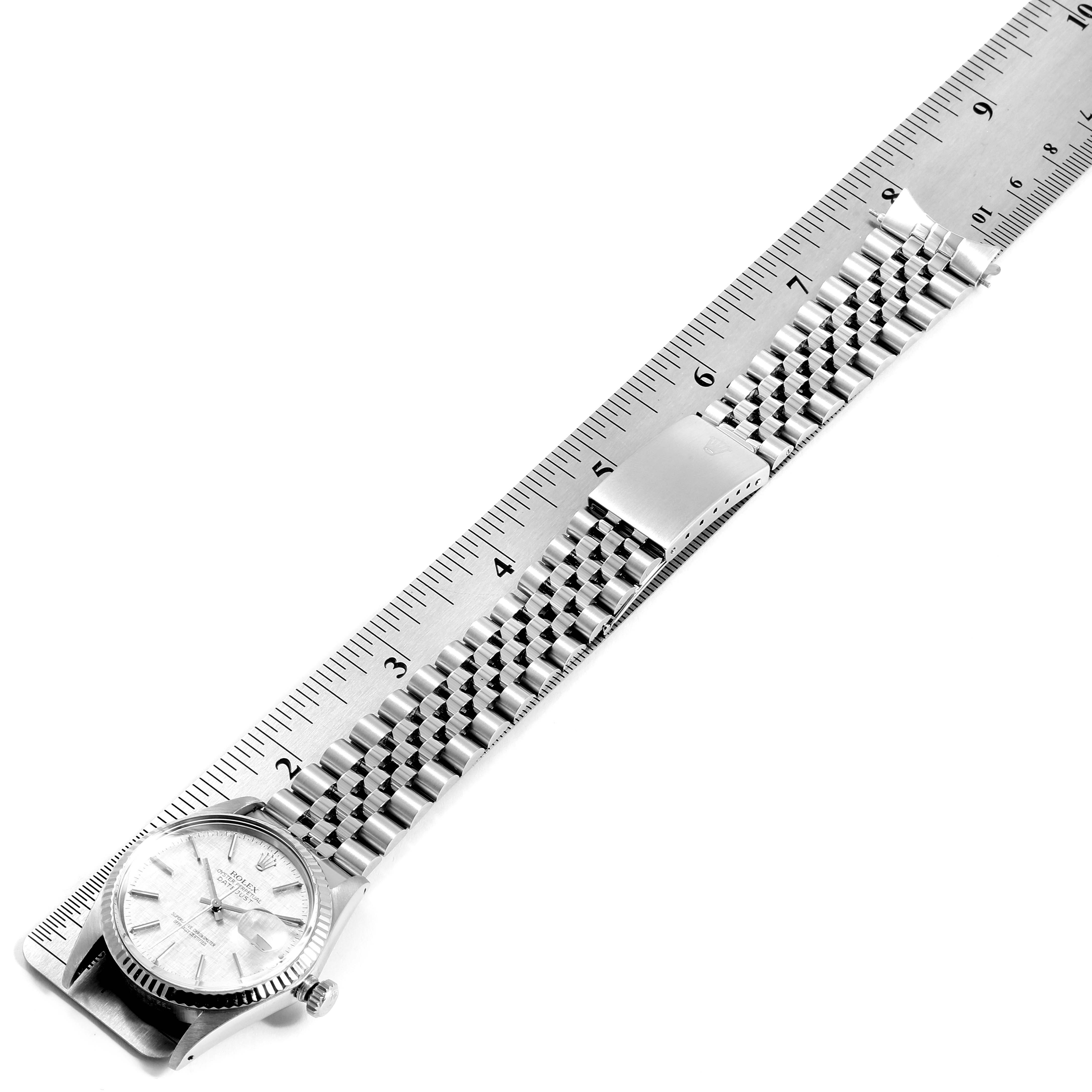 This image shows a top view of the Rolex Vintage Collection 16014 Men
s Stainless Steel Silver Dial 16014 Men
s Stainless Steel Silver Dial watch, displaying the full length of the watch band along with a metal ruler for scale.