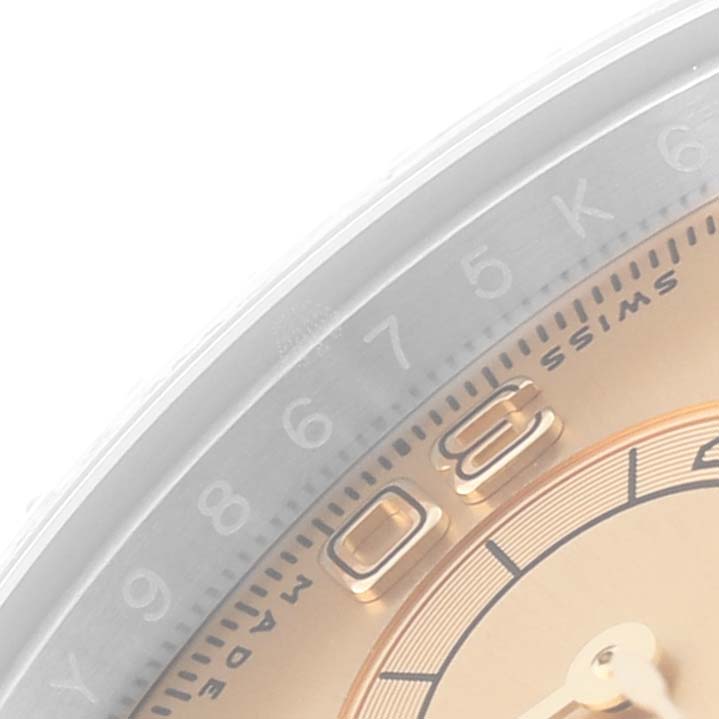This close-up image of a Rolex Daytona 116503 Men's Steel and Gold (two tone) Champagne Dial 116503 Men's Steel and Gold (two tone) Champagne Dial watch shows part of the bezel with markings and a part of the dial with hour markers.