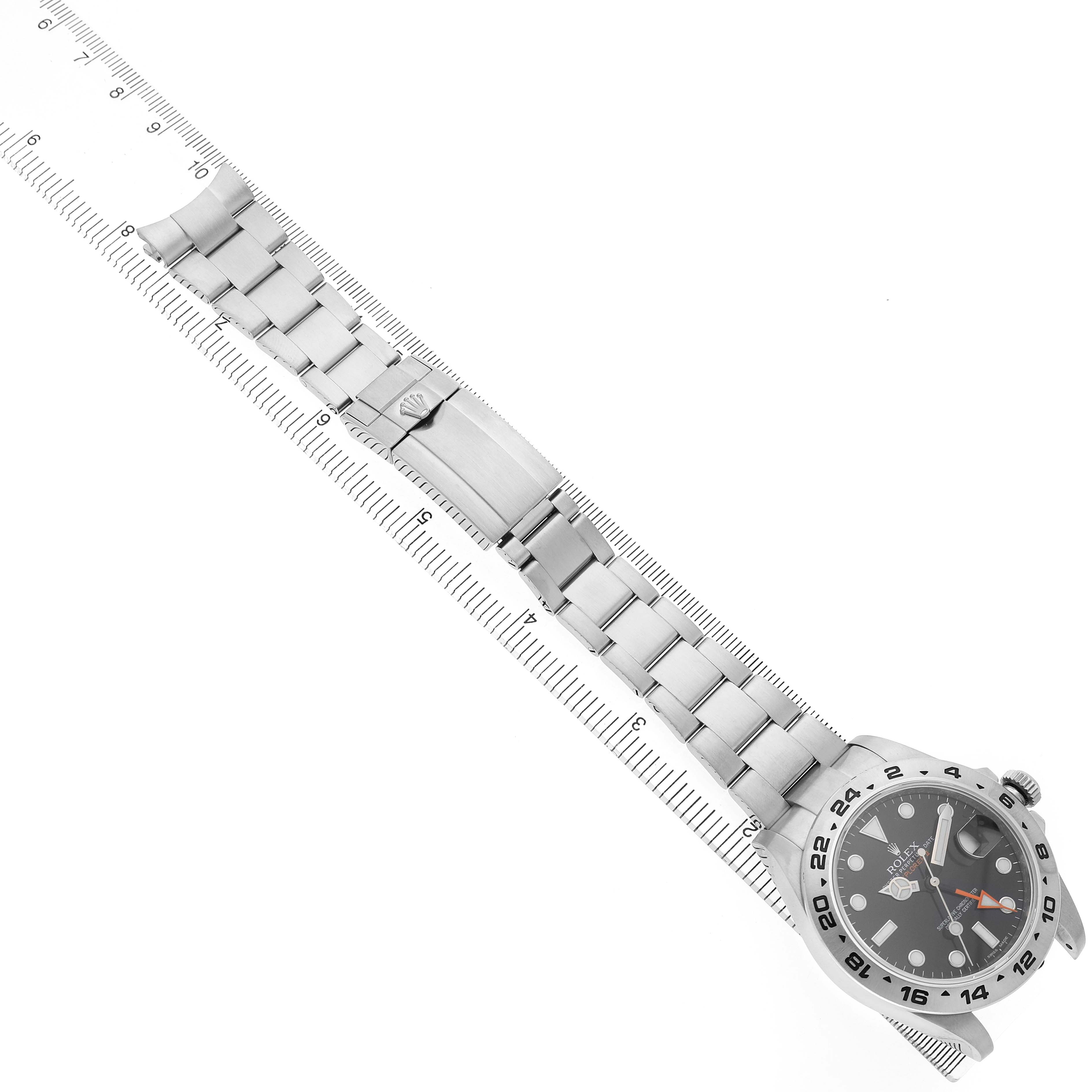 The image shows a bird's-eye view of a Rolex Explorer 216570 Men's Stainless Steel Black Dial watch with a metal bracelet, aligned along a measuring ruler.