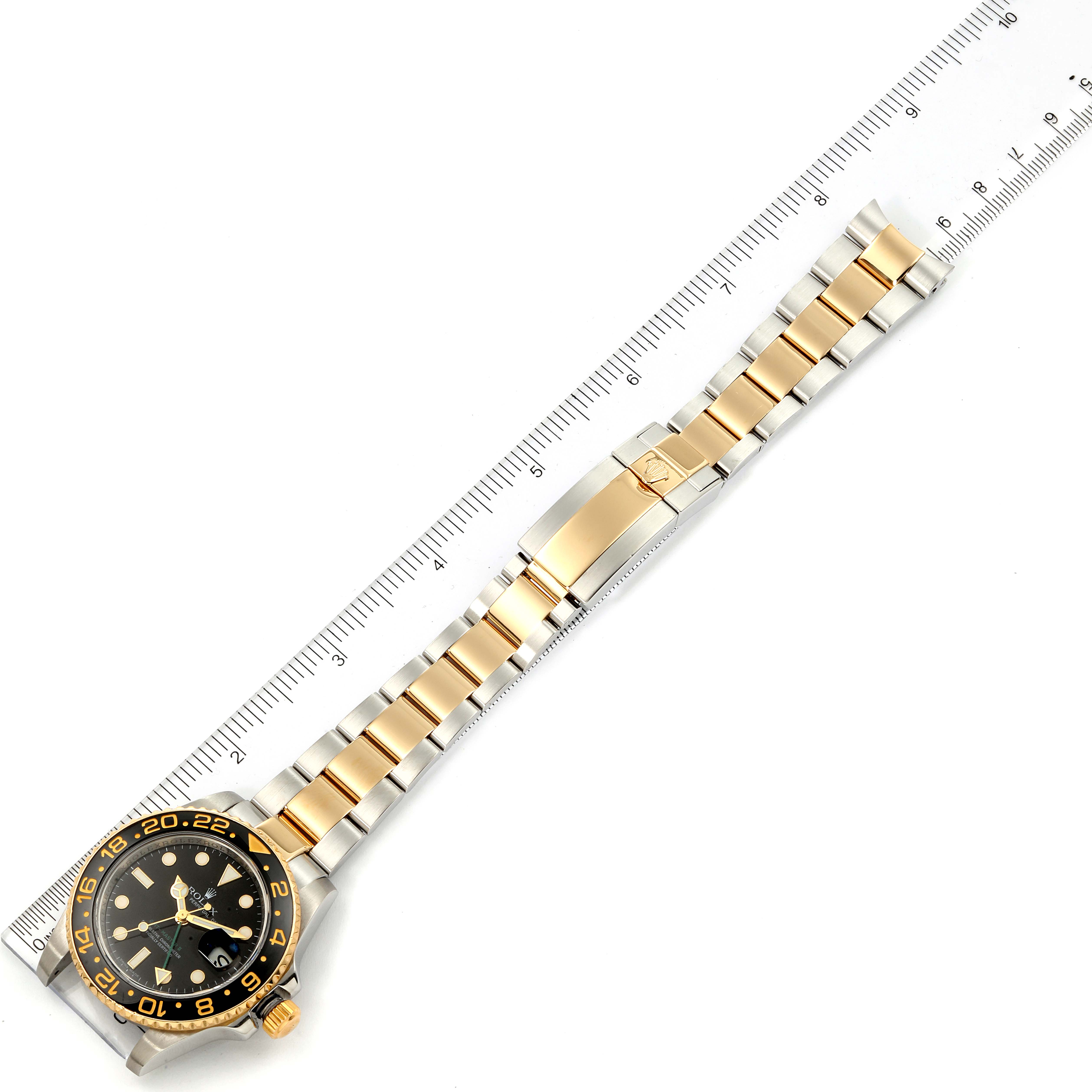 The image shows a Rolex GMT-Master 116713 Men's Steel and Gold (two tone) Black Dial 116713 Men's Steel and Gold (two tone) Black Dial watch, focusing on the face and bracelet, aligned with a measuring ruler.
