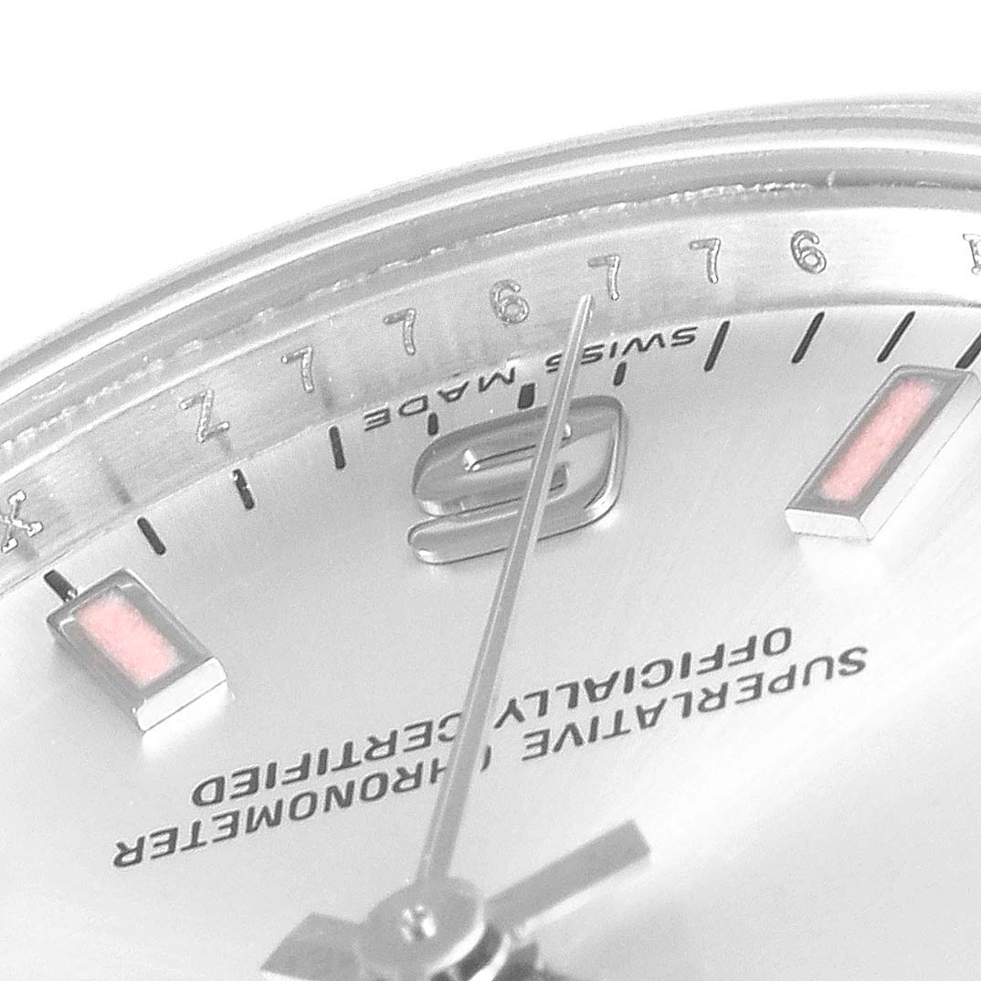 This close-up image shows the face and hour markers of a Mid-Size Rolex watch, viewed at an angle.