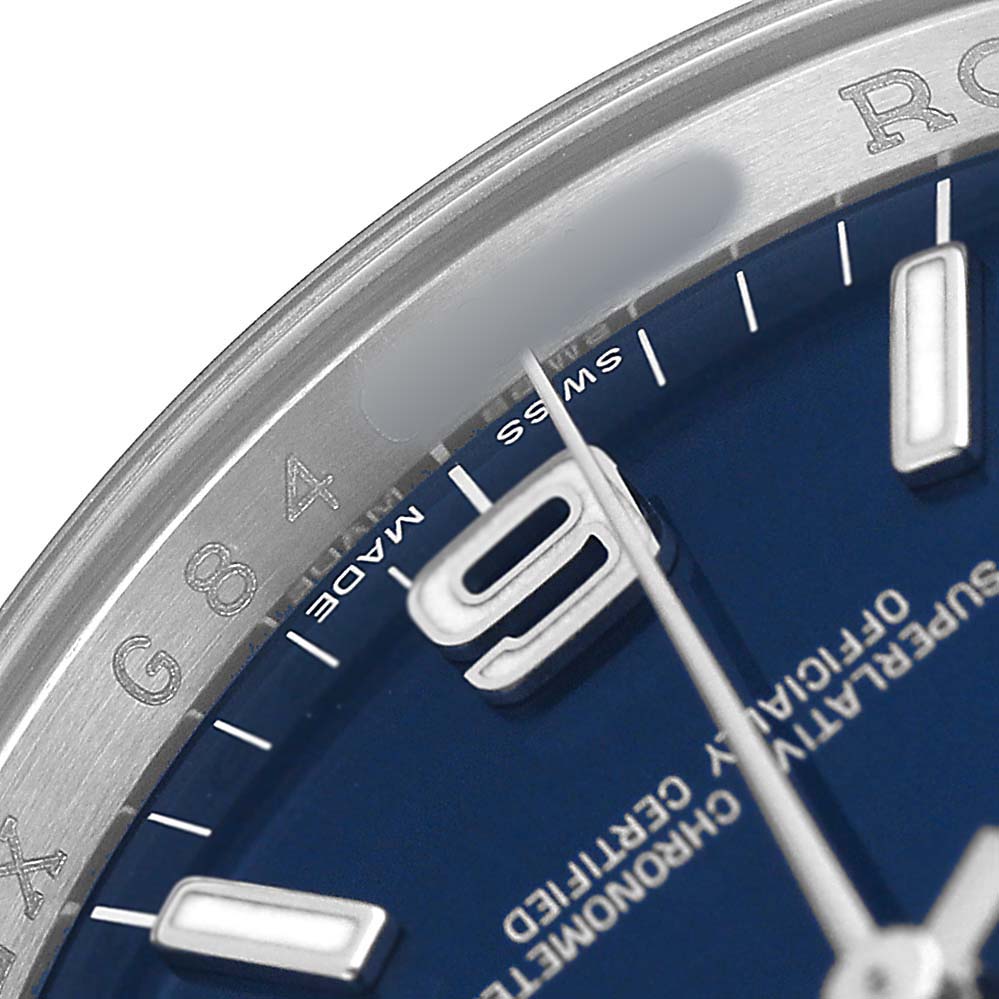 The image shows a close-up of the dial and bezel of a Rolex Oyster Perpetual 116000 Men's Stainless Steel Blue Dial watch, highlighting the numbers and text details.
