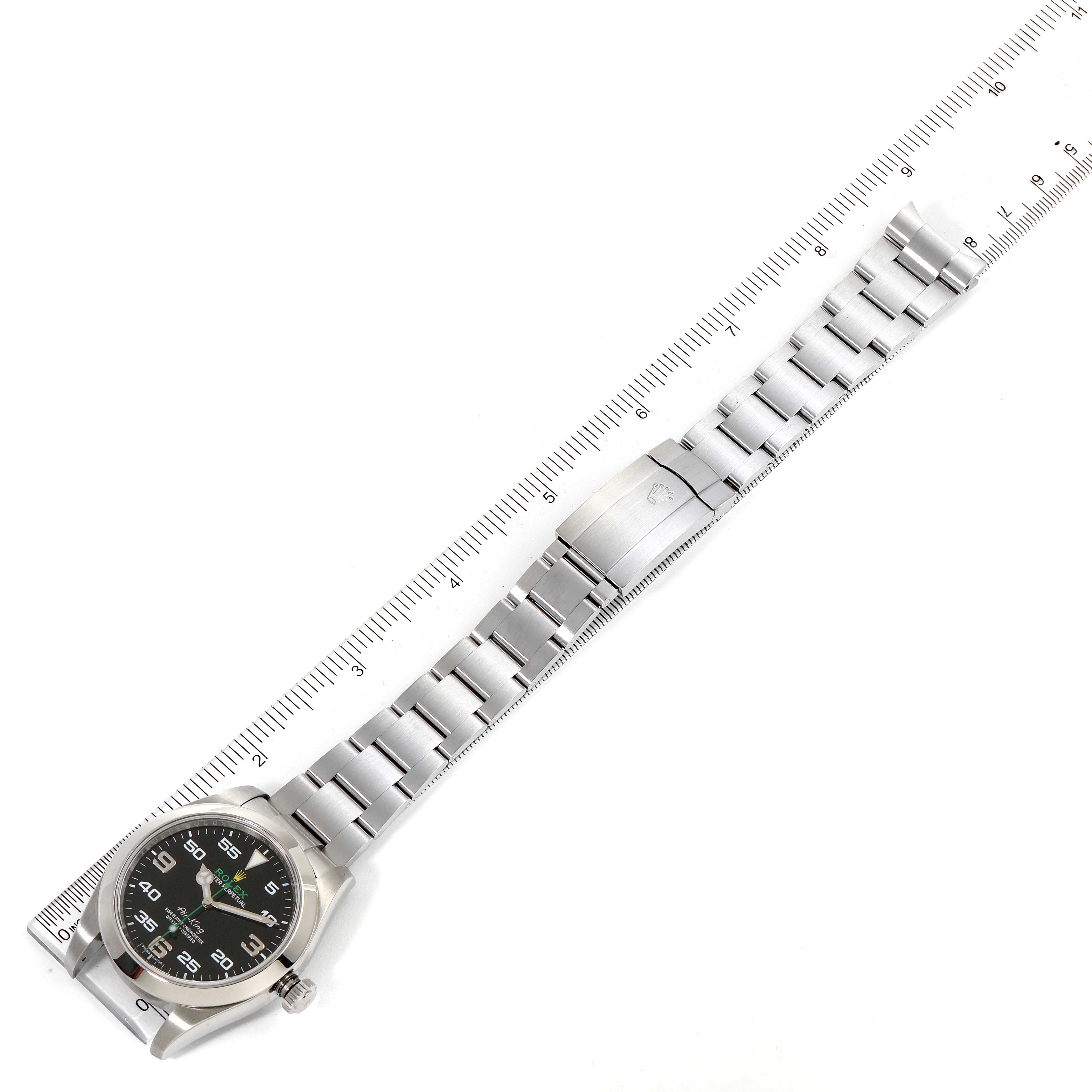 The Rolex Air-King 116900 Men's Stainless Steel Black Dial 116900 Men's Stainless Steel Black Dial watch is shown from a top-down angle, displaying the face, bracelet, and clasp, alongside a measuring scale.