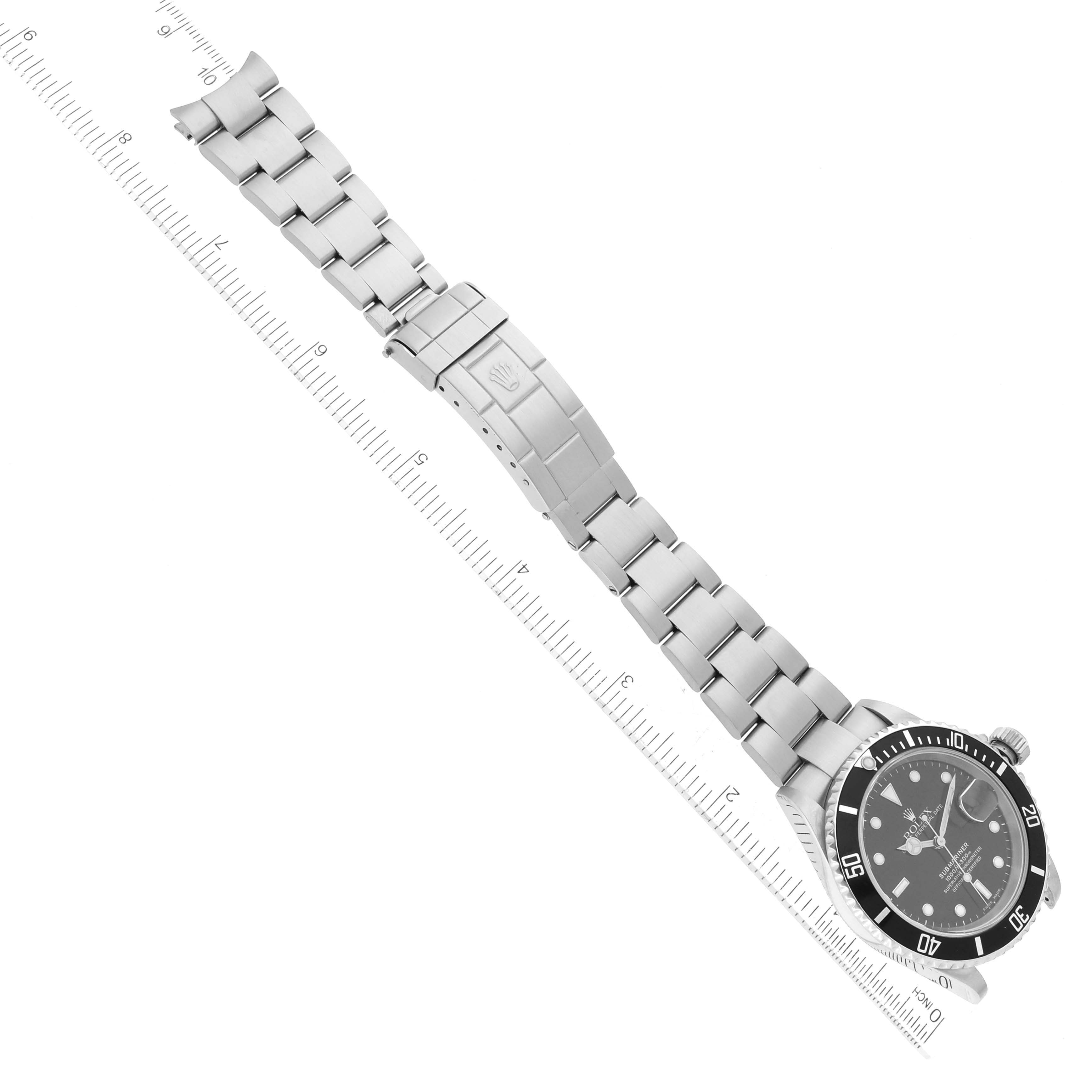 This image shows the front view of a Rolex Submariner 16610 Men
s Stainless Steel Black Dial 16610 Men
s Stainless Steel Black Dial watch, including the dial, bezel, bracelet, and clasp measured against a ruler.