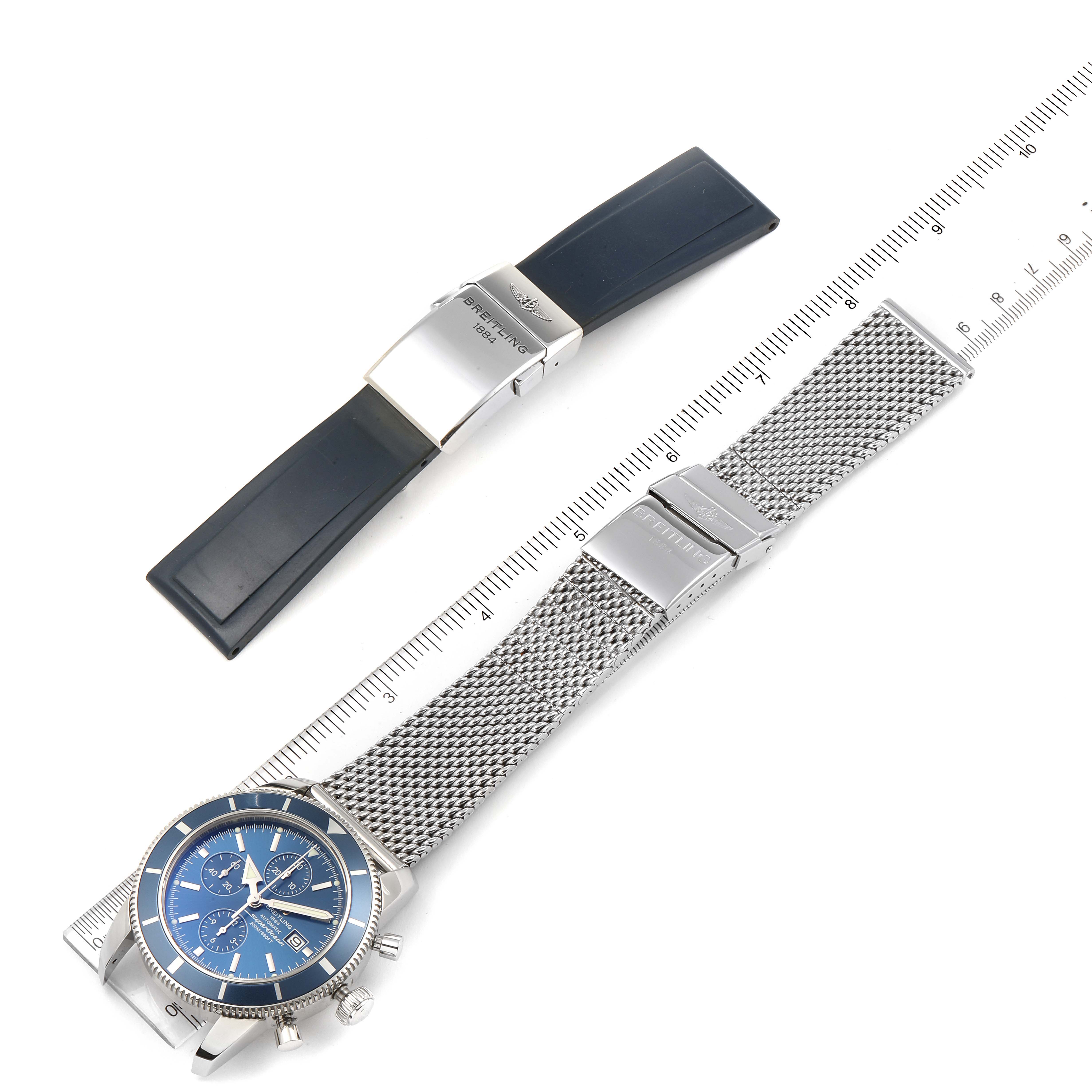 The image shows a top-down view of a Breitling Superocean A13320 Men
s Stainless Steel Blue Dial A13320 Men
s Stainless Steel Blue Dial watch with a blue dial and a metal mesh strap, alongside a black rubber strap.