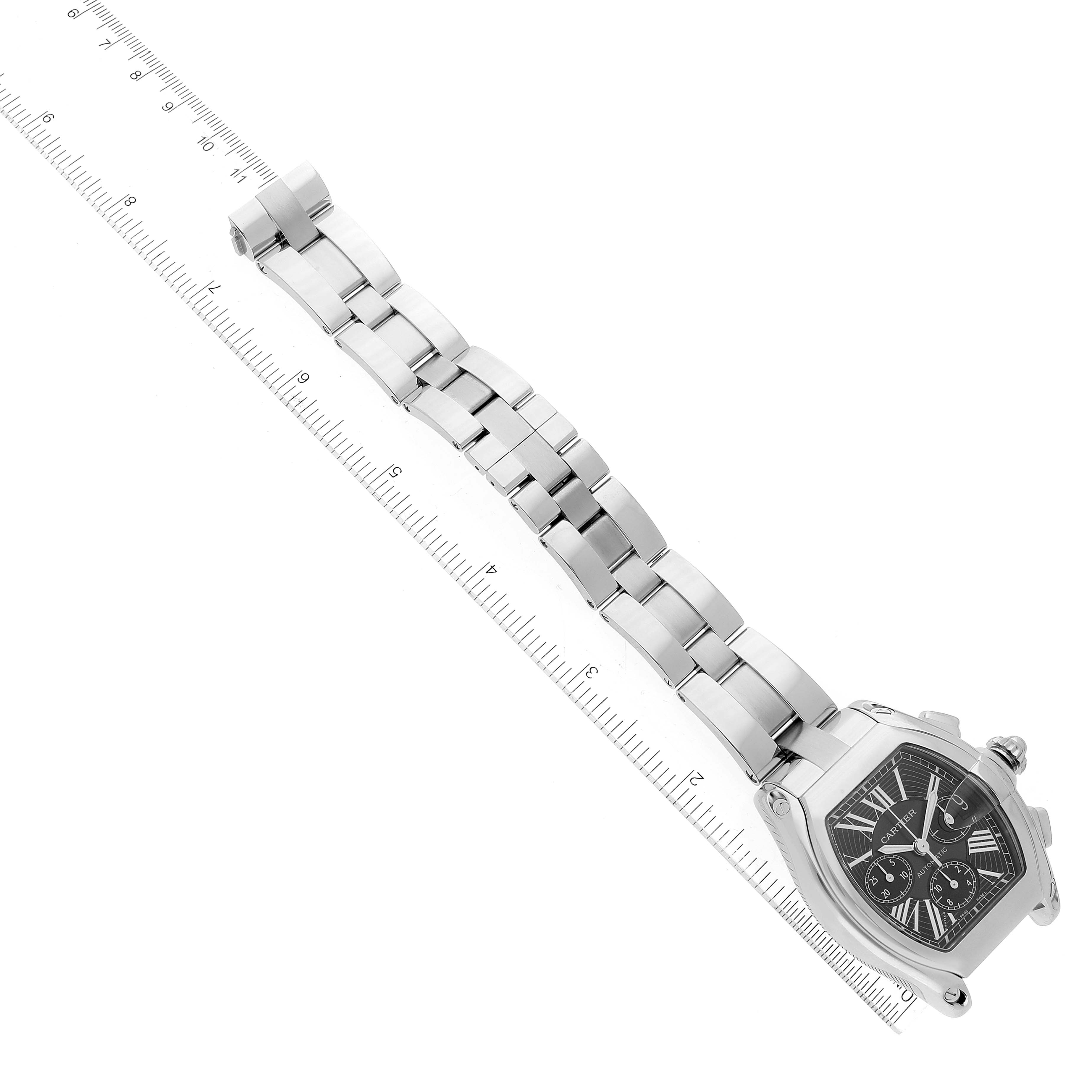 This image shows a top-down view of a Cartier Roadster W62007X6 Men's Stainless Steel Black Dial W62007X6 Men's Stainless Steel Black Dial watch displaying the face and full metal bracelet beside a ruler for scale.