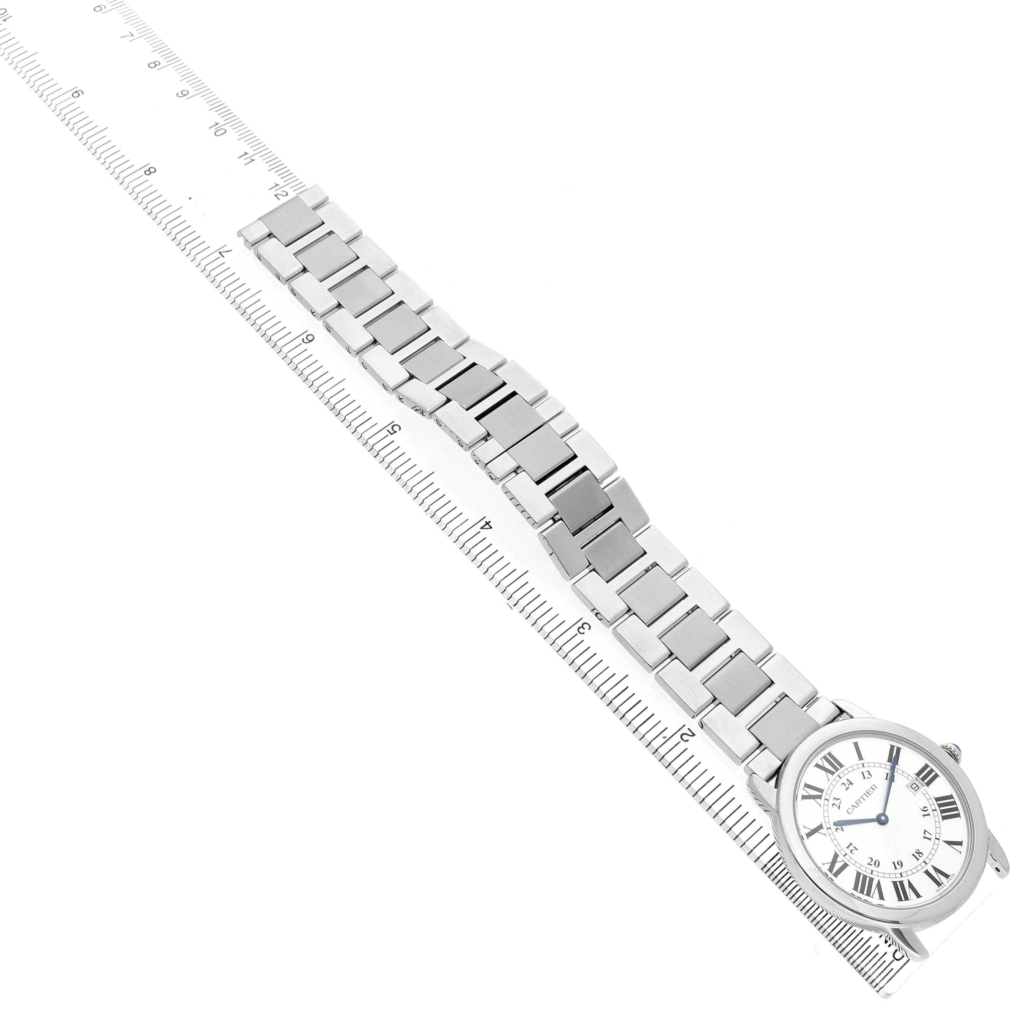 The Cartier Ronde W6701005 Men's Stainless Steel Silver Dial watch is shown at a diagonal angle, displaying both the face and metal bracelet fully extended, alongside a ruler.