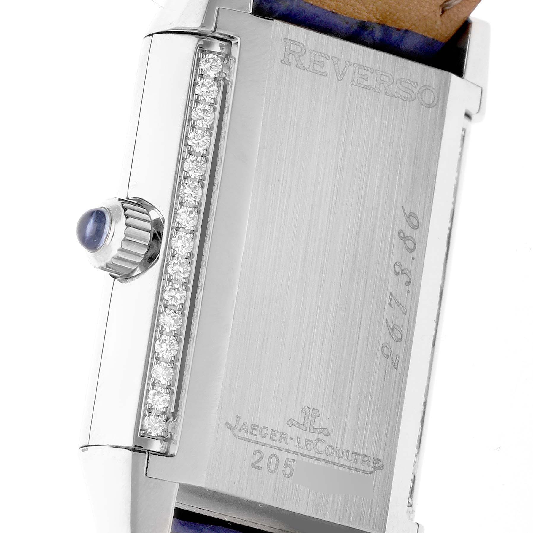 The image shows the side of a Jaeger-LeCoultre Reverso watch, highlighting the crown, diamond detailing, and engraved case back.