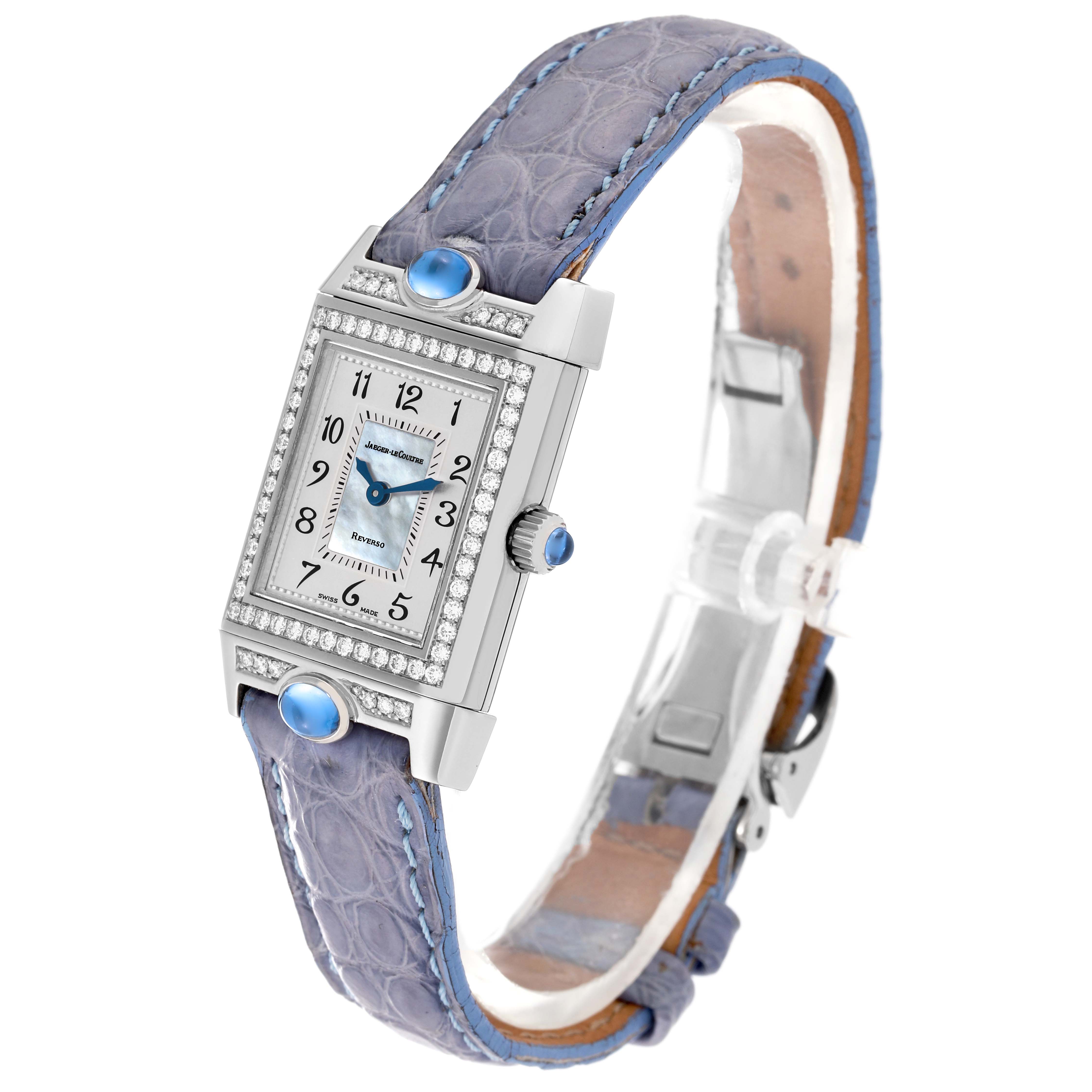 This Jaeger LeCoultre Reverso Q2623403 Women's White Gold Mother of Pearl Dial Q2623403 Women's White Gold Mother of Pearl Dial watch is shown at a slight angle, highlighting its face, blue strap, crown, and rectangular diamond-set bezel.