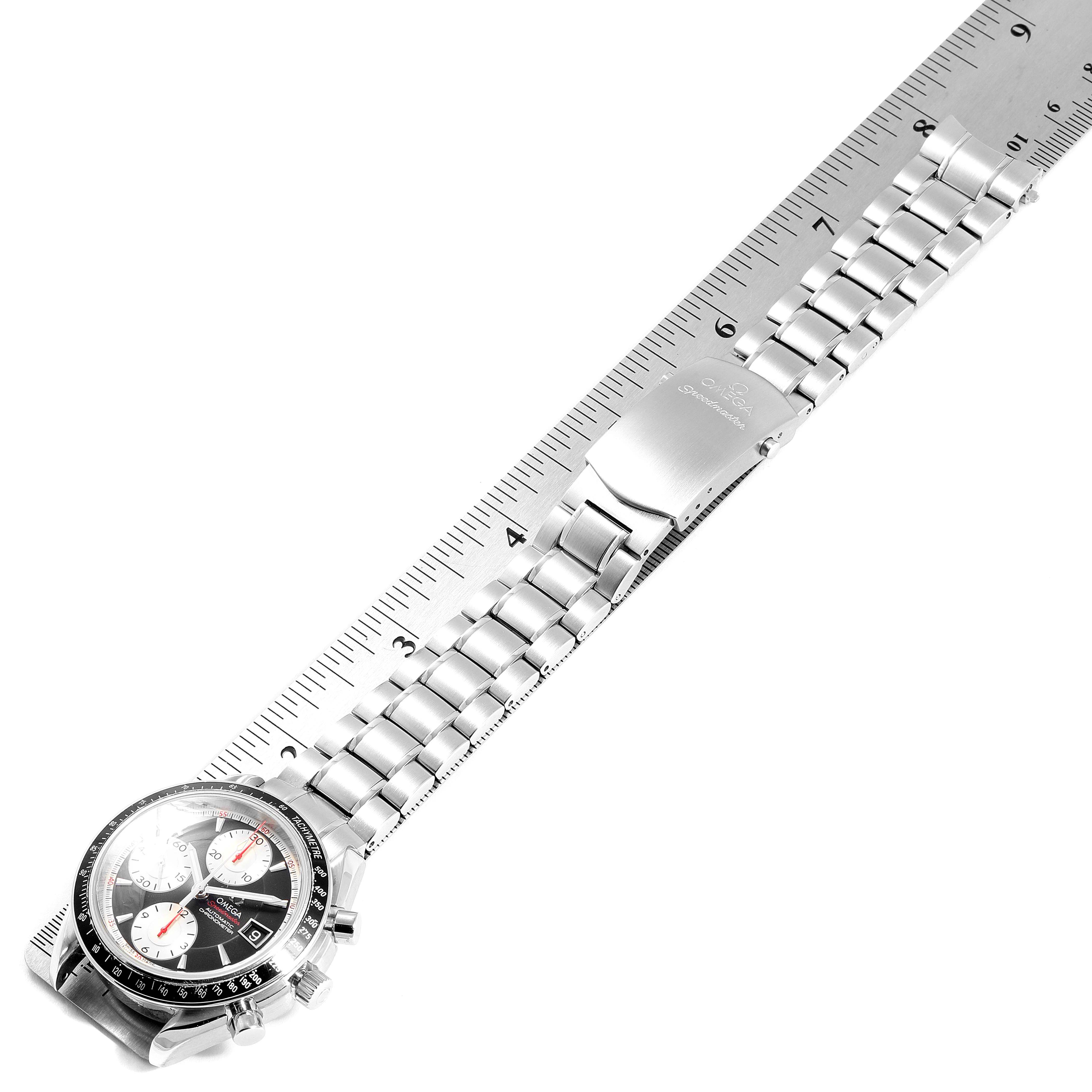 The image shows an overhead view of an Omega Speedmaster 3210.51.00 Men's Stainless Steel Black Dial 3210.51.00 Men's Stainless Steel Black Dial watch with the case, dial, and metal bracelet visible next to a ruler.
